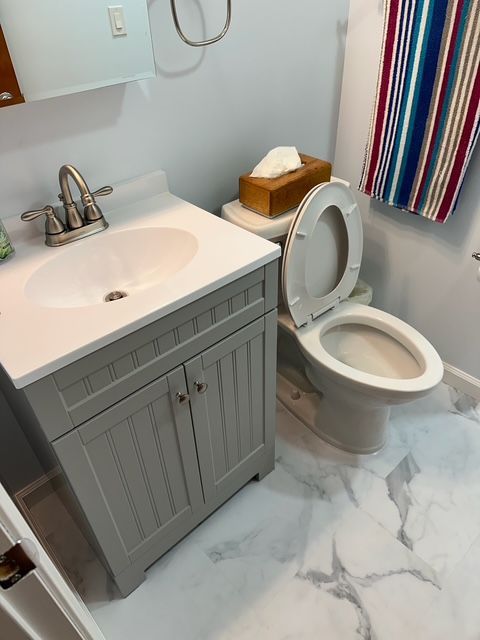 A bathroom with a toilet a sink and a striped shower curtain