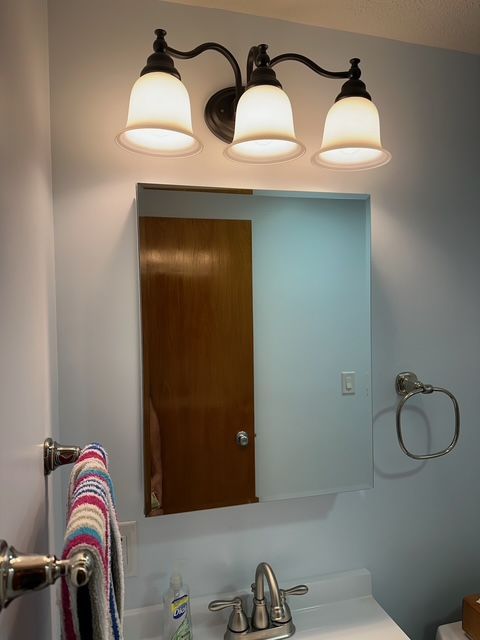 A bathroom with a sink , mirror and towel rack