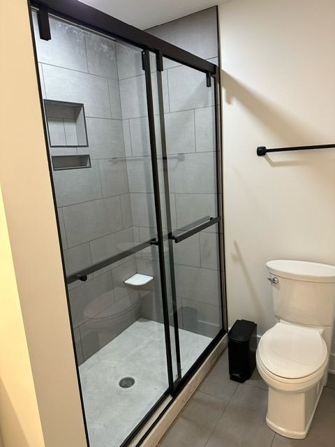 A bathroom with a toilet and shower with sliding glass doors