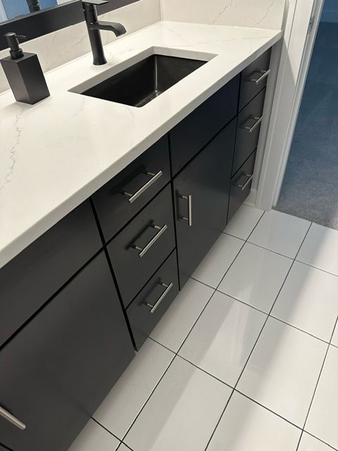 A bathroom with black cabinets and a black sink
