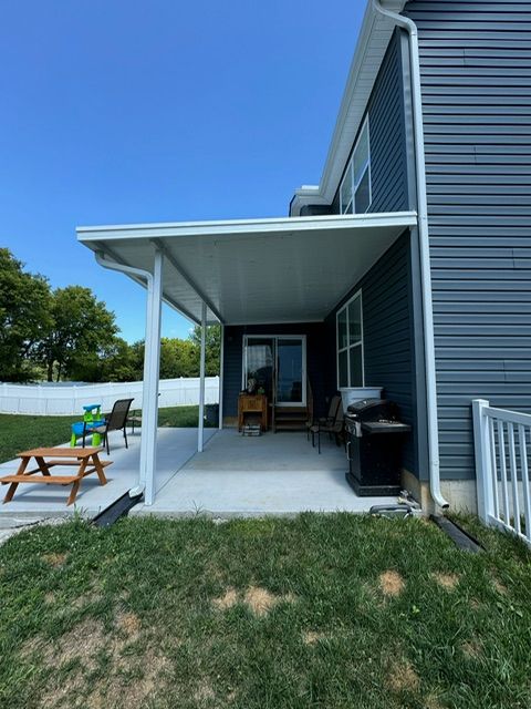 The backyard of a house with a covered patio and a picnic table.