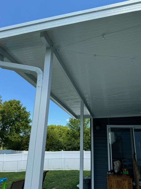 A white patio cover is sitting on top of a blue house.