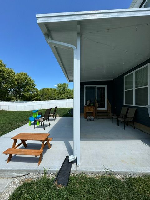 A covered patio with a picnic table and chairs
