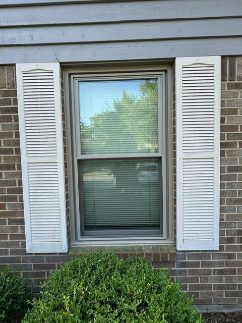 A window with white shutters on a brick building