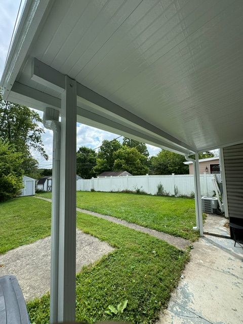 A porch with a white roof and a white fence in the background.