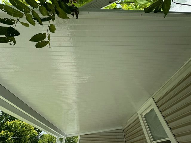 The roof of a house with a porch and trees in the background.