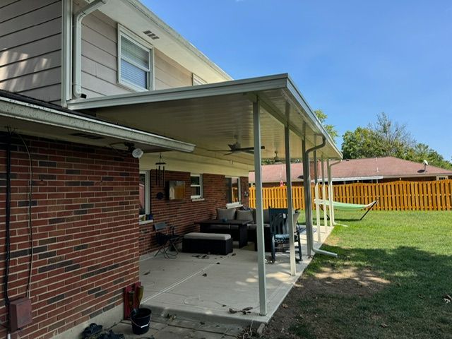 A brick house with a covered patio in the backyard.