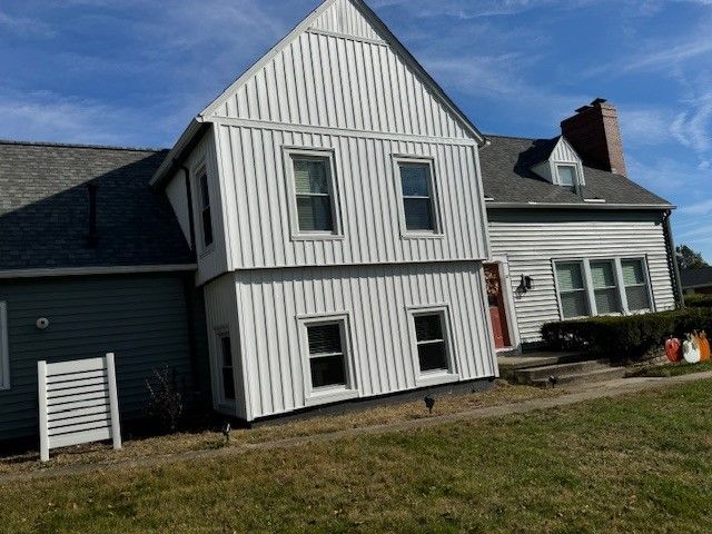 A white house with a gray roof and a red door