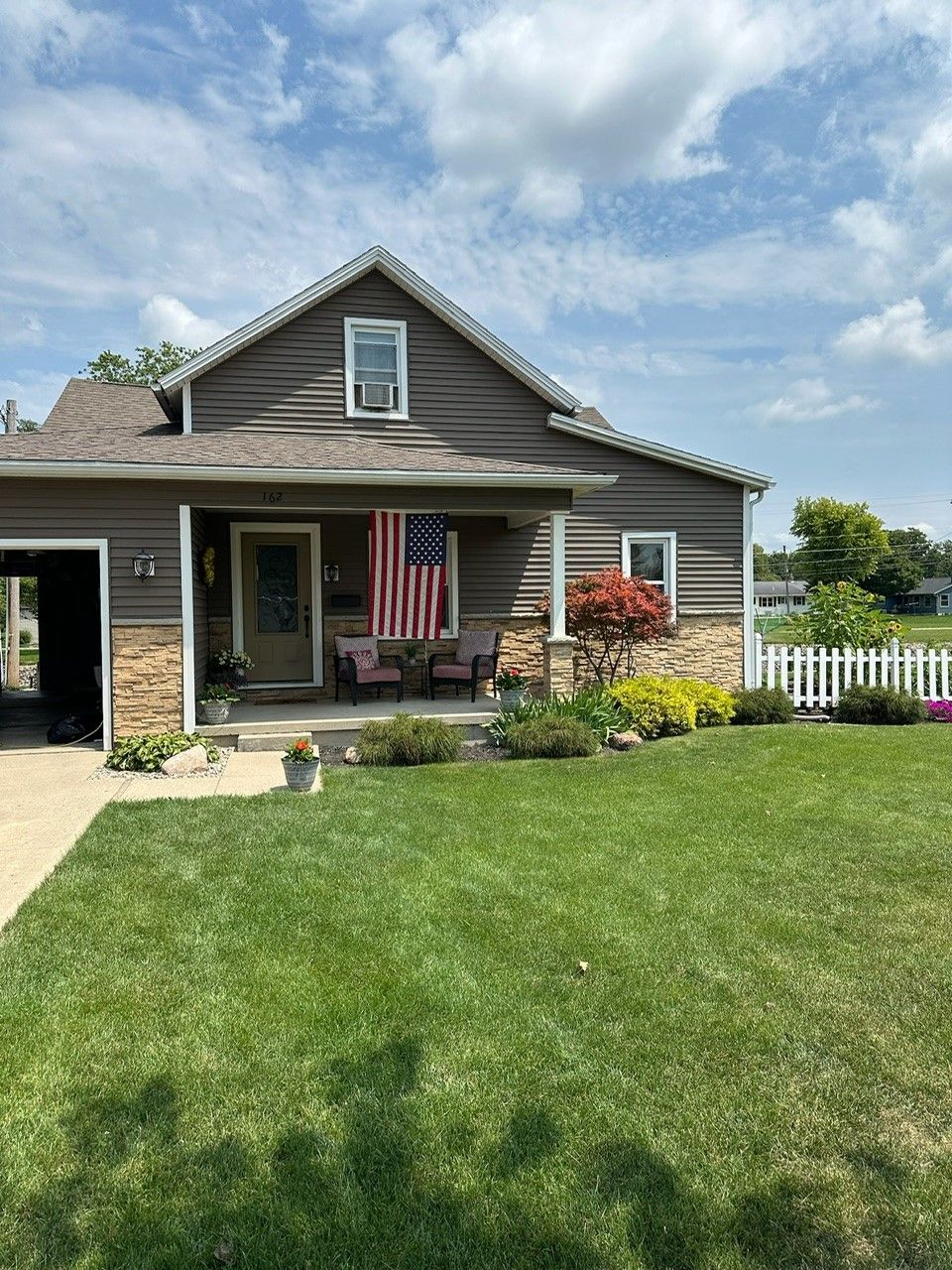 A house with a large lawn and an american flag on the porch.