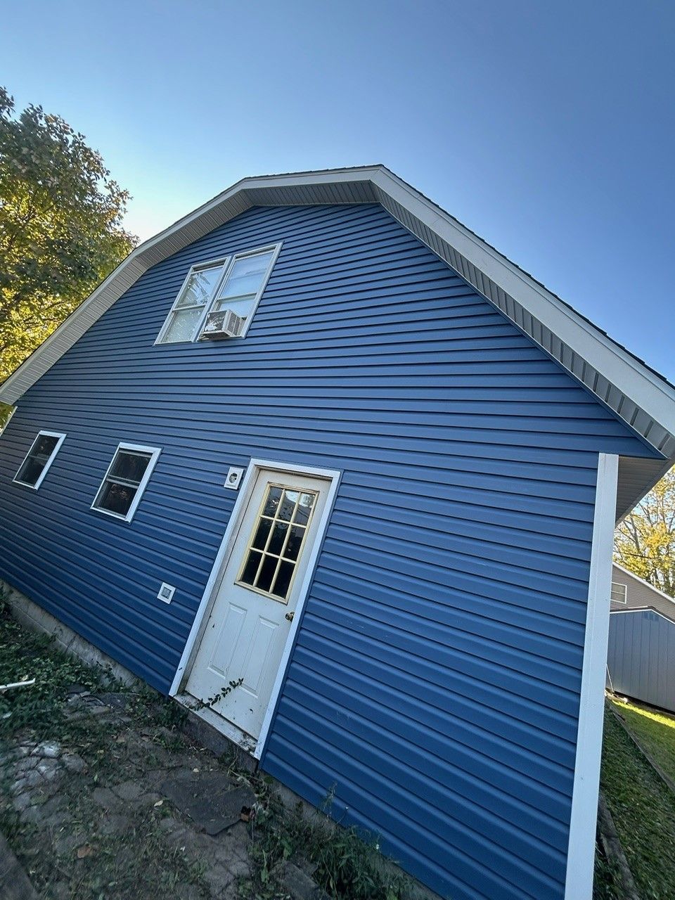 A blue house with a white door and windows on a sunny day.