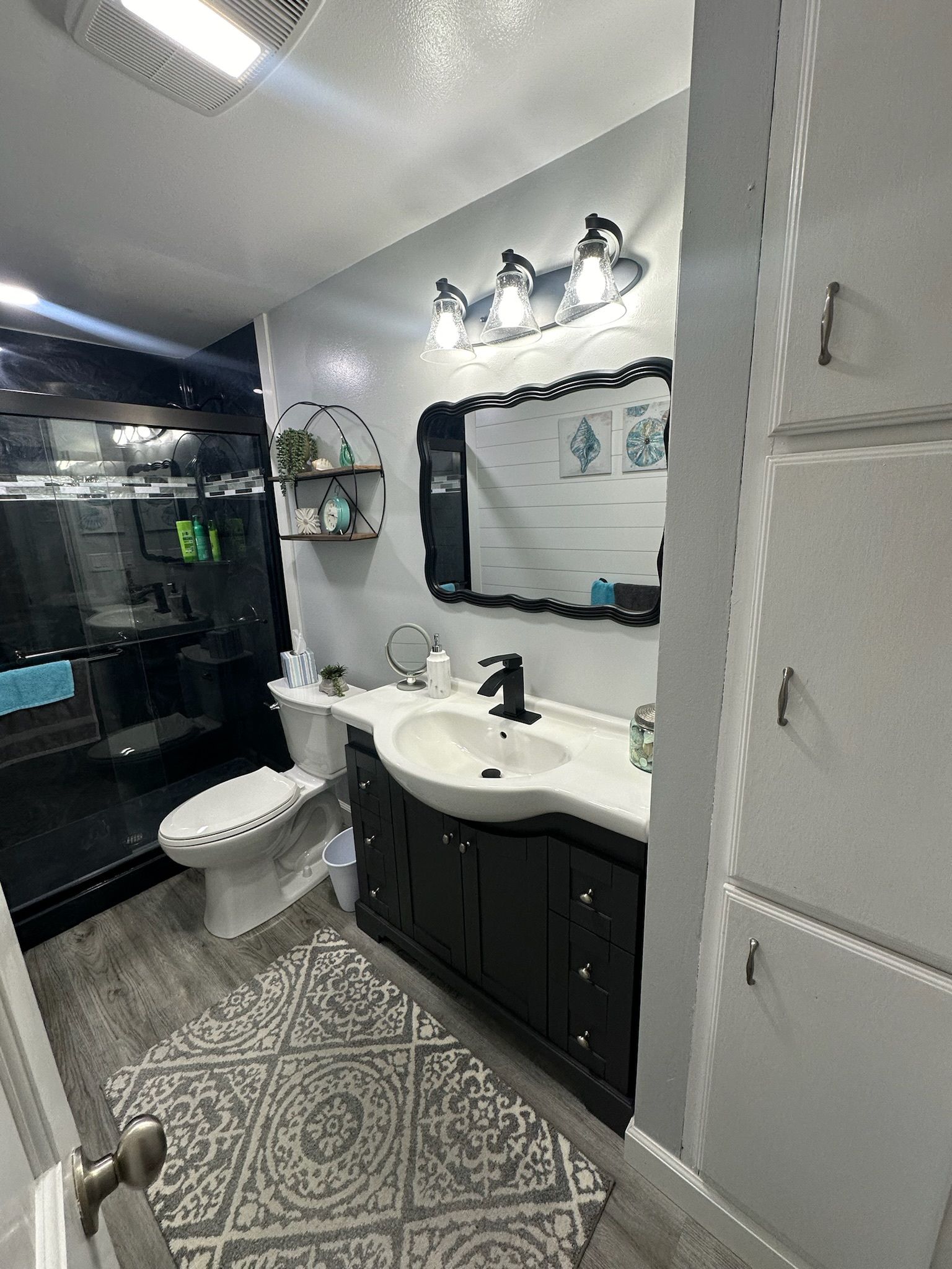 A bathroom with a sink, toilet, mirror and rug.