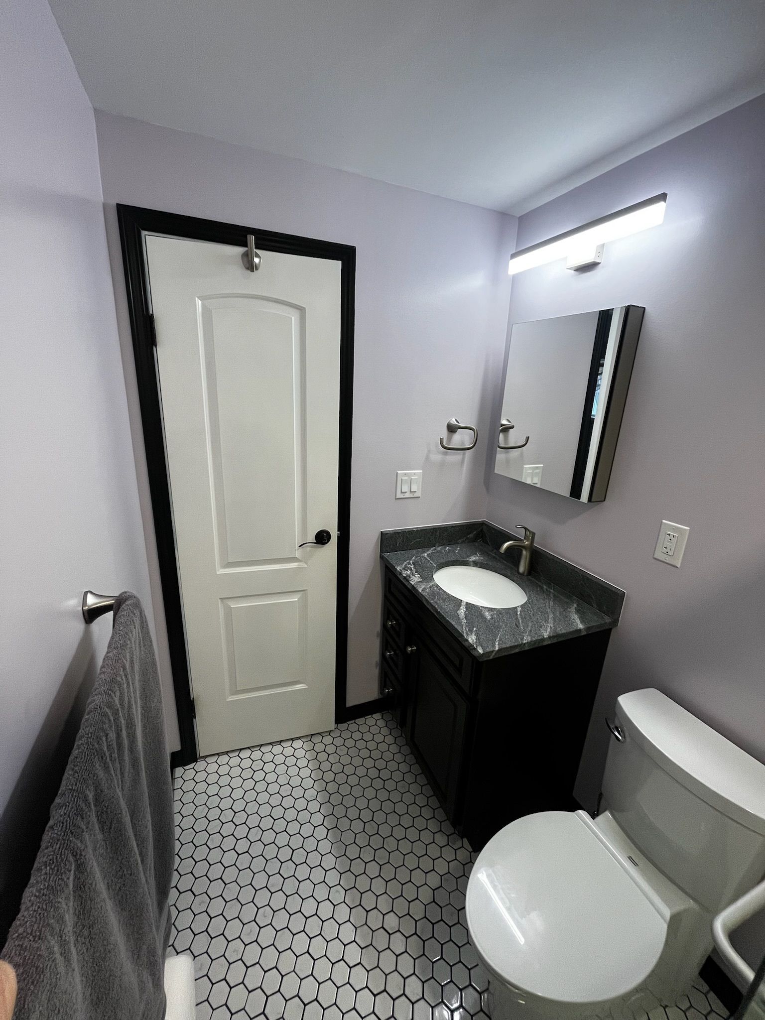 A bathroom with a toilet, sink and mirror.