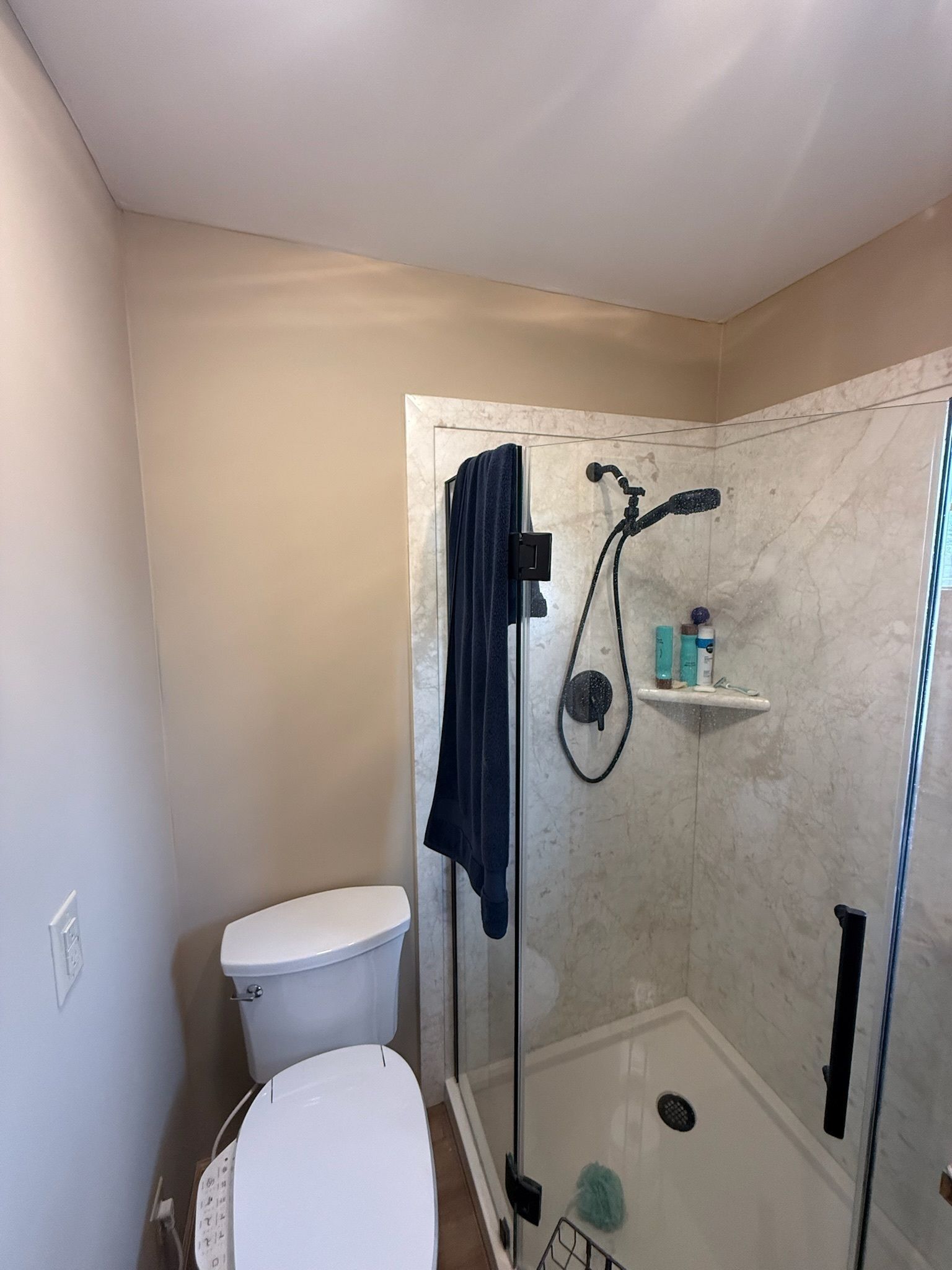A bathroom with a toilet, shower, and towel rack.