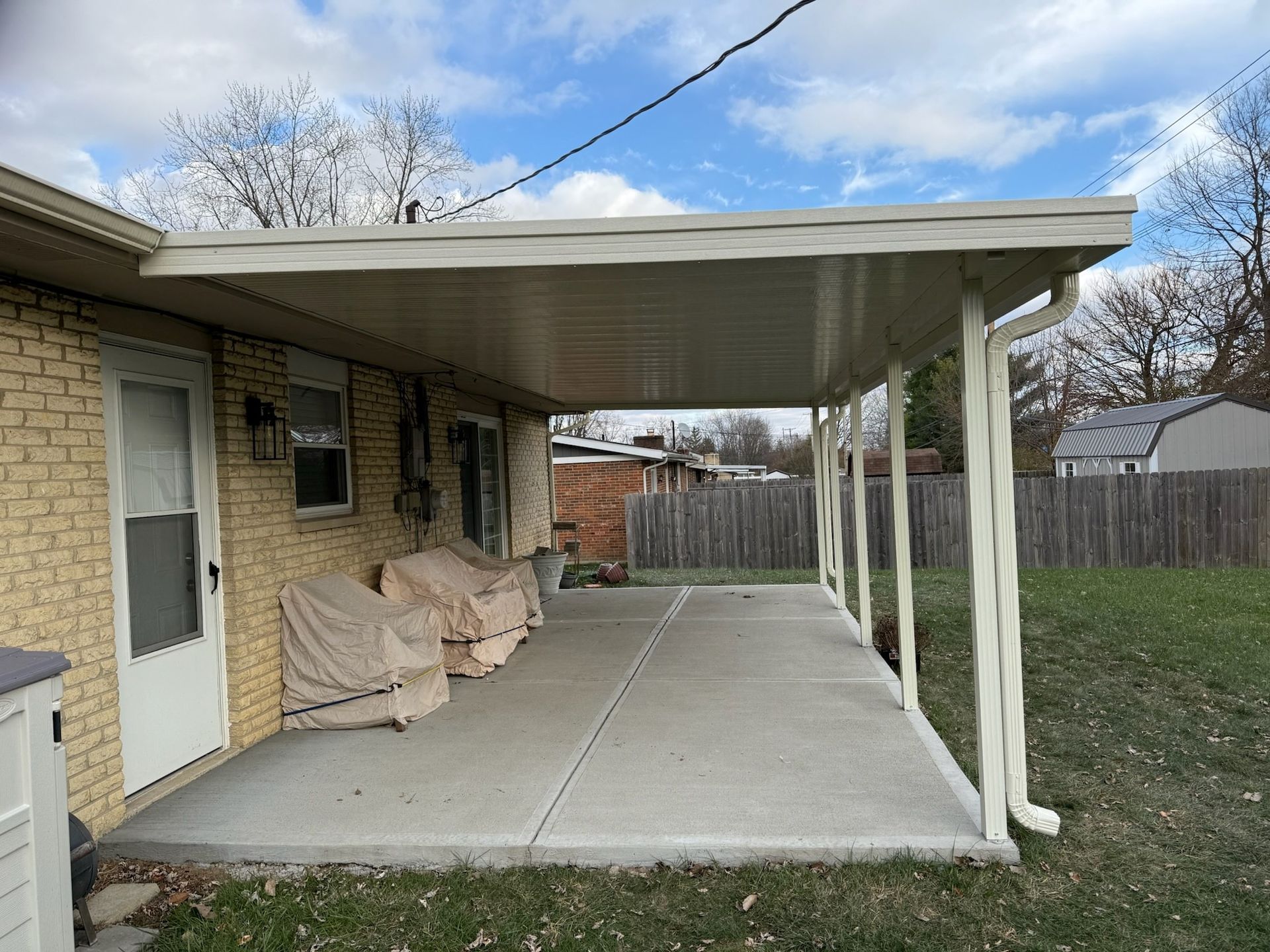 A brick house with a covered porch and a white roof.