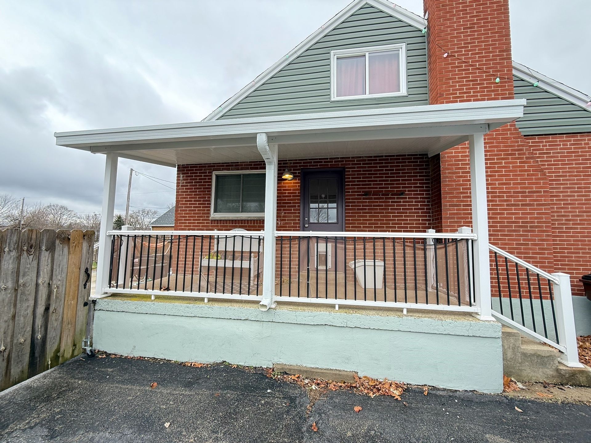 A brick house with a porch and a white railing.