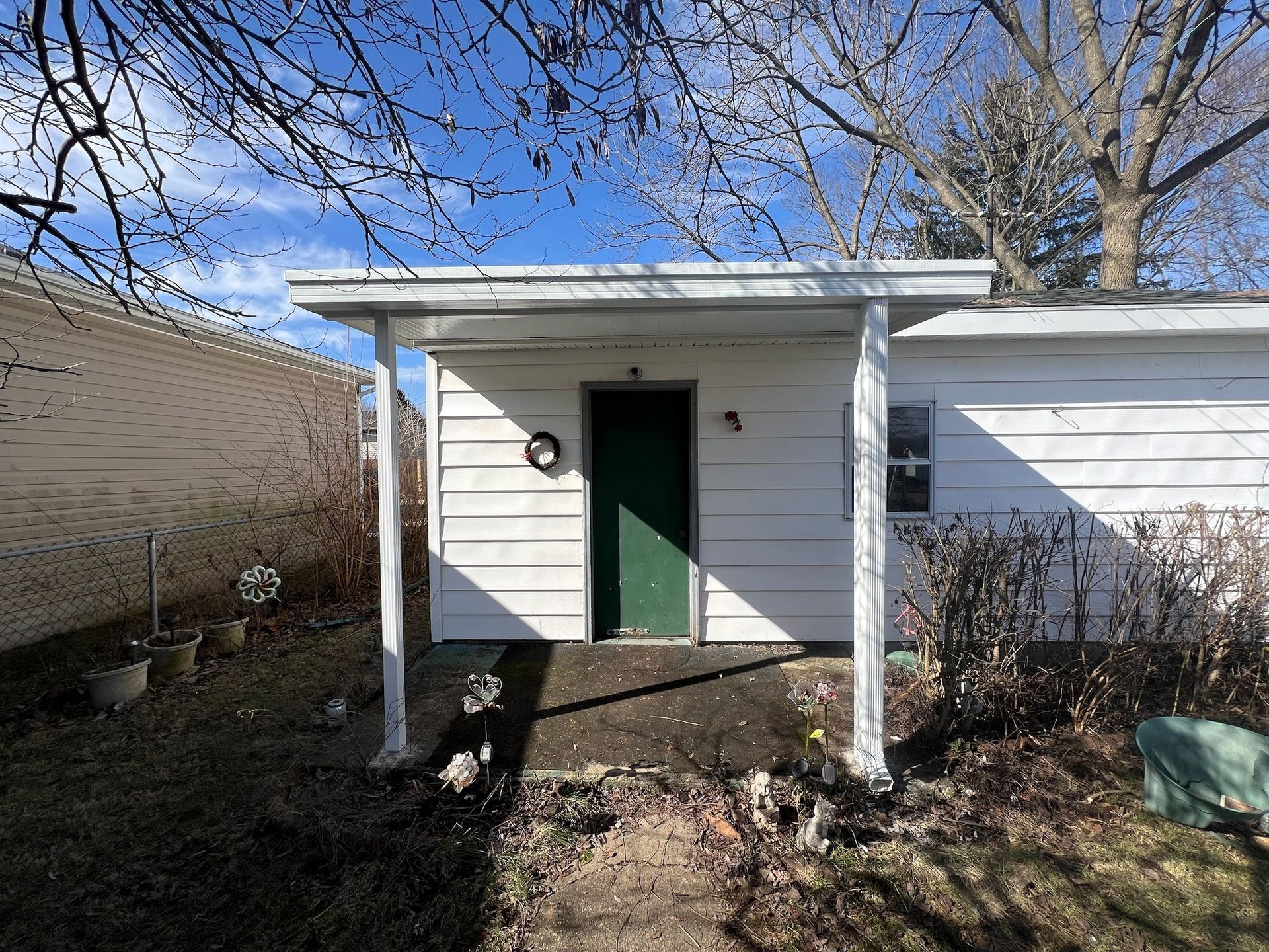 A small white house with a green door and a porch.