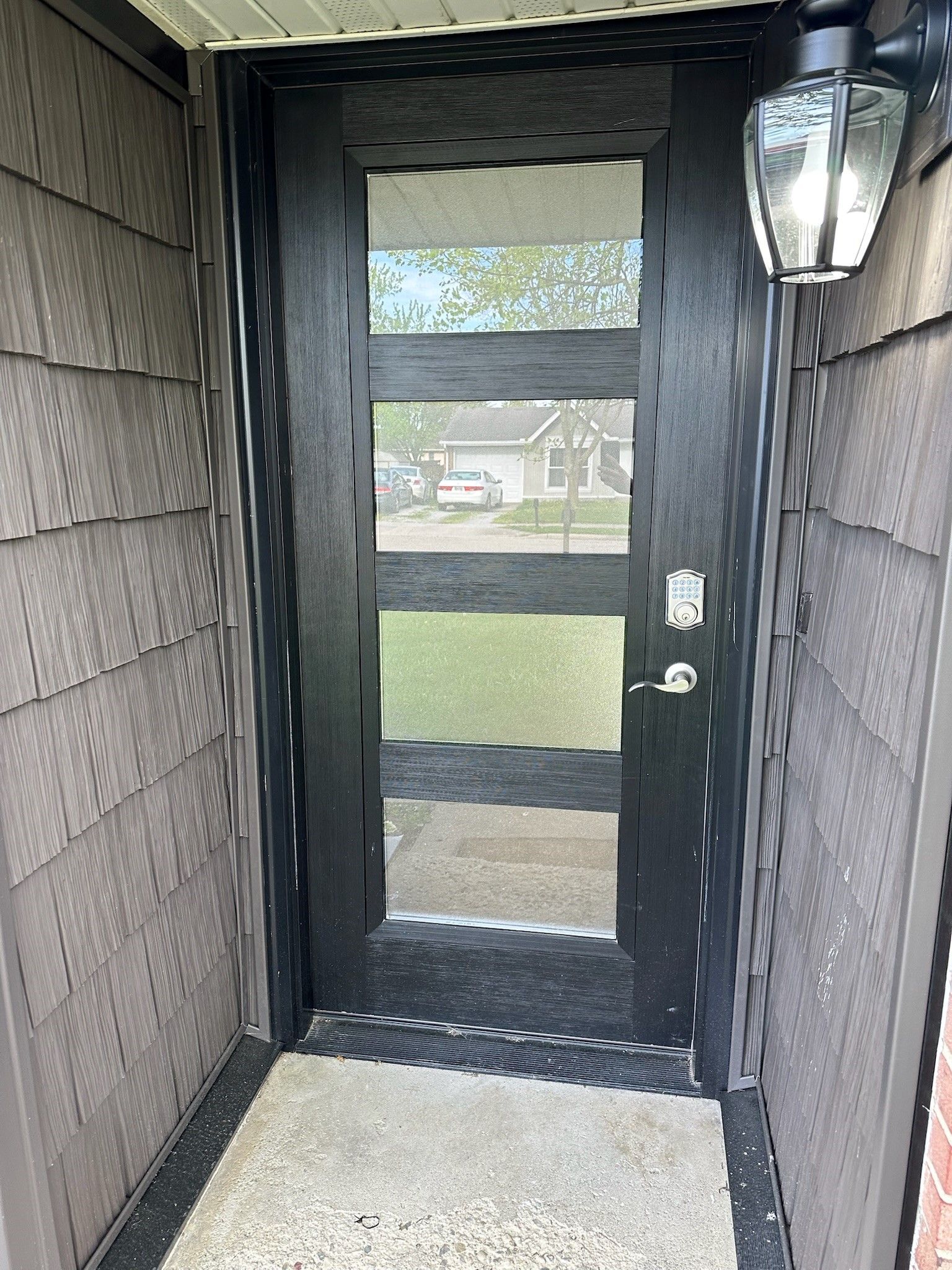A black door with a lantern on the side of it.