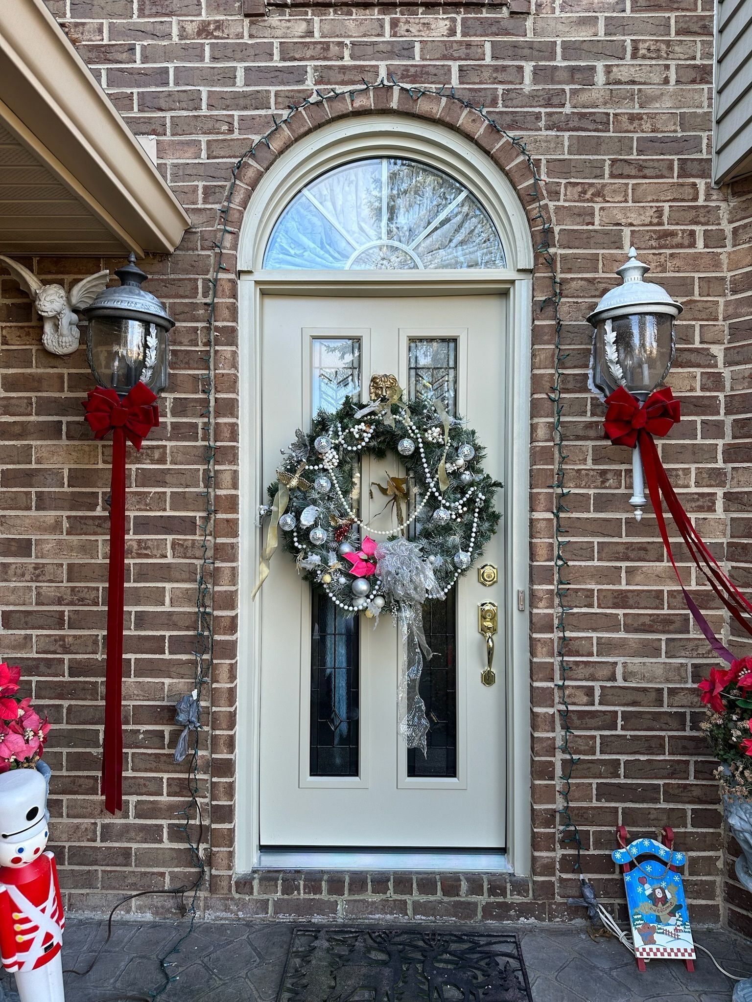 The front door of a brick house decorated for christmas with a wreath on it.