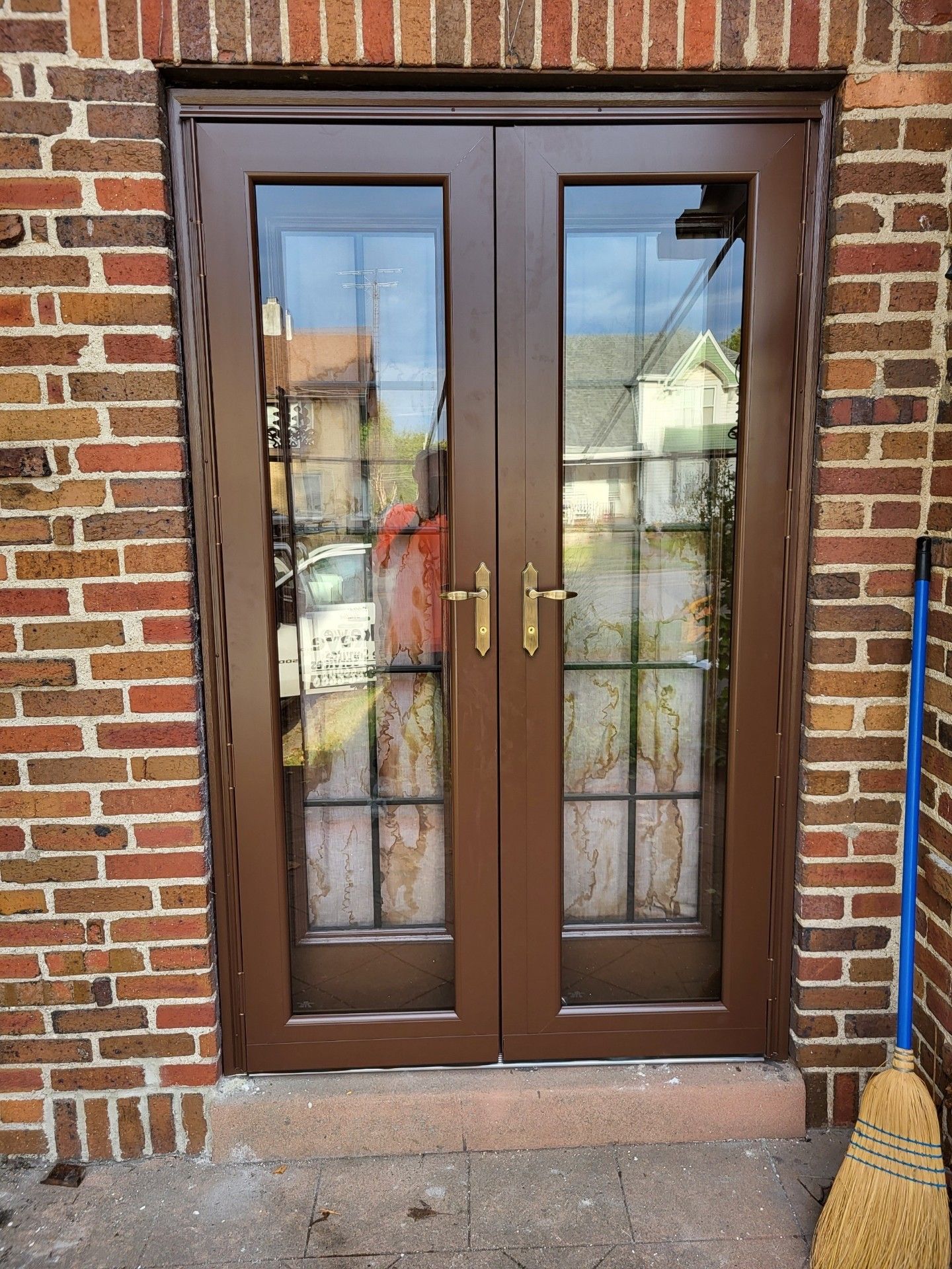 A brick building with a wooden door and a broom.
