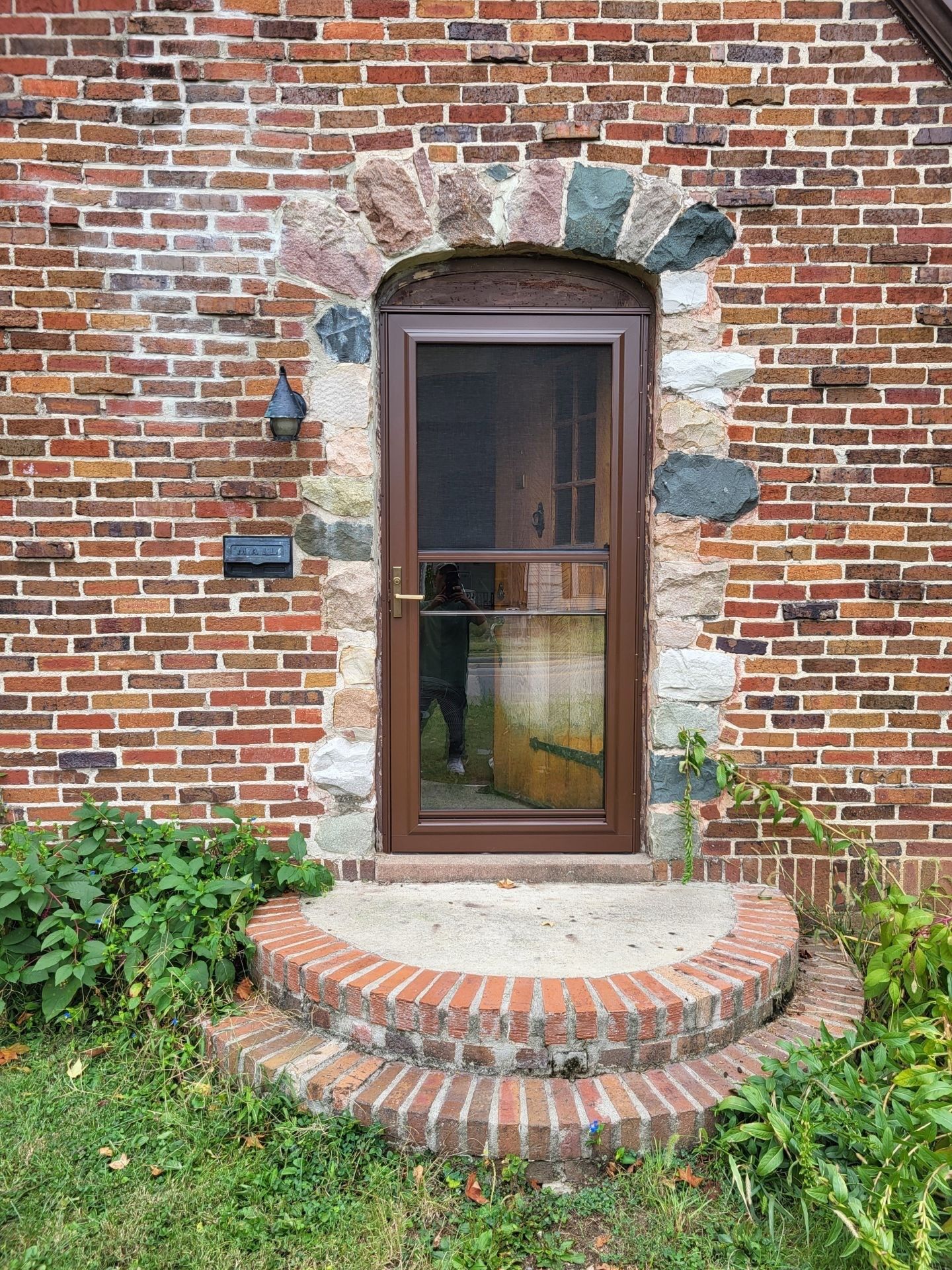 A brick building with a screen door and stone archway.