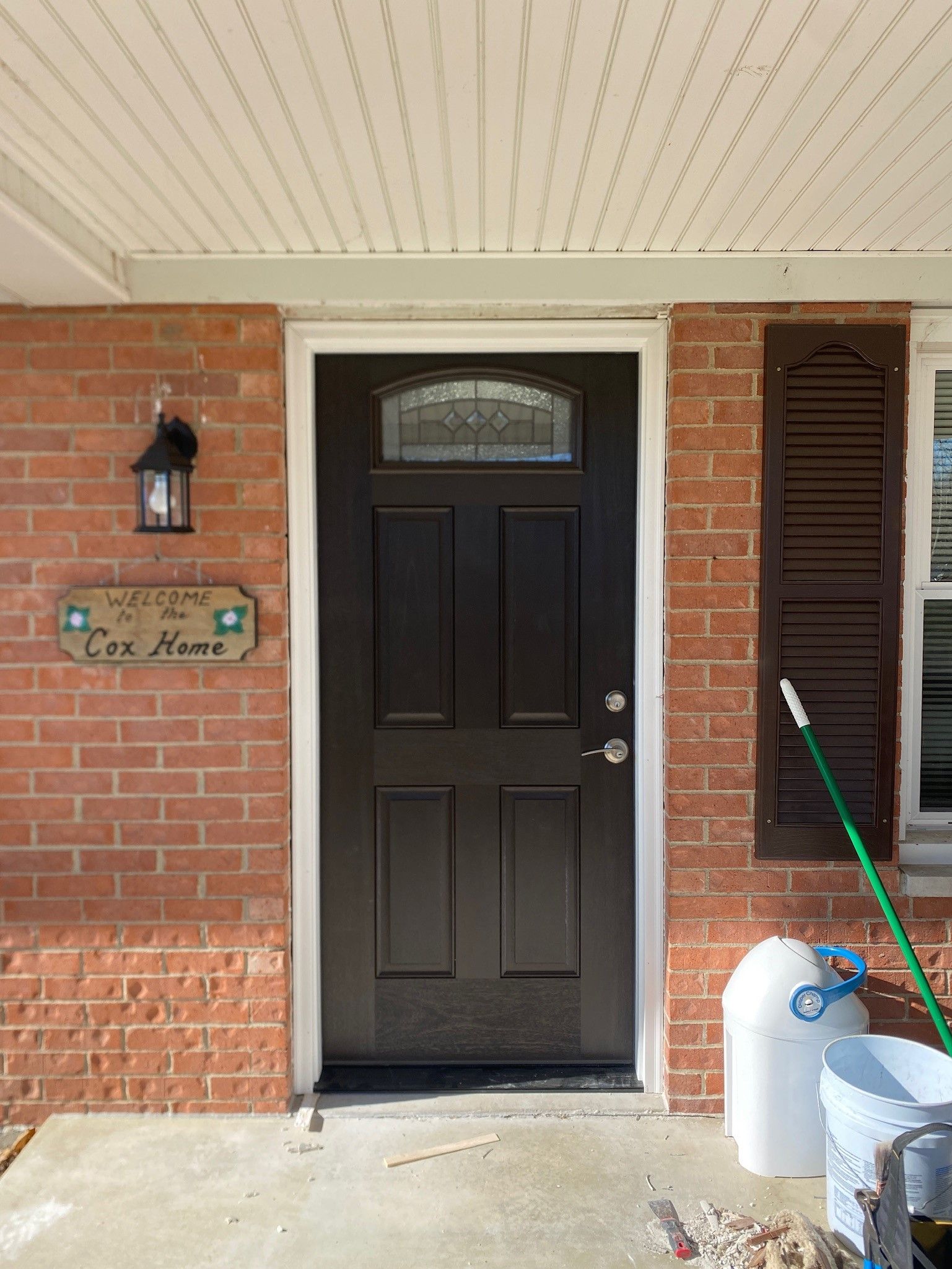 The front door of a brick house with a black door.