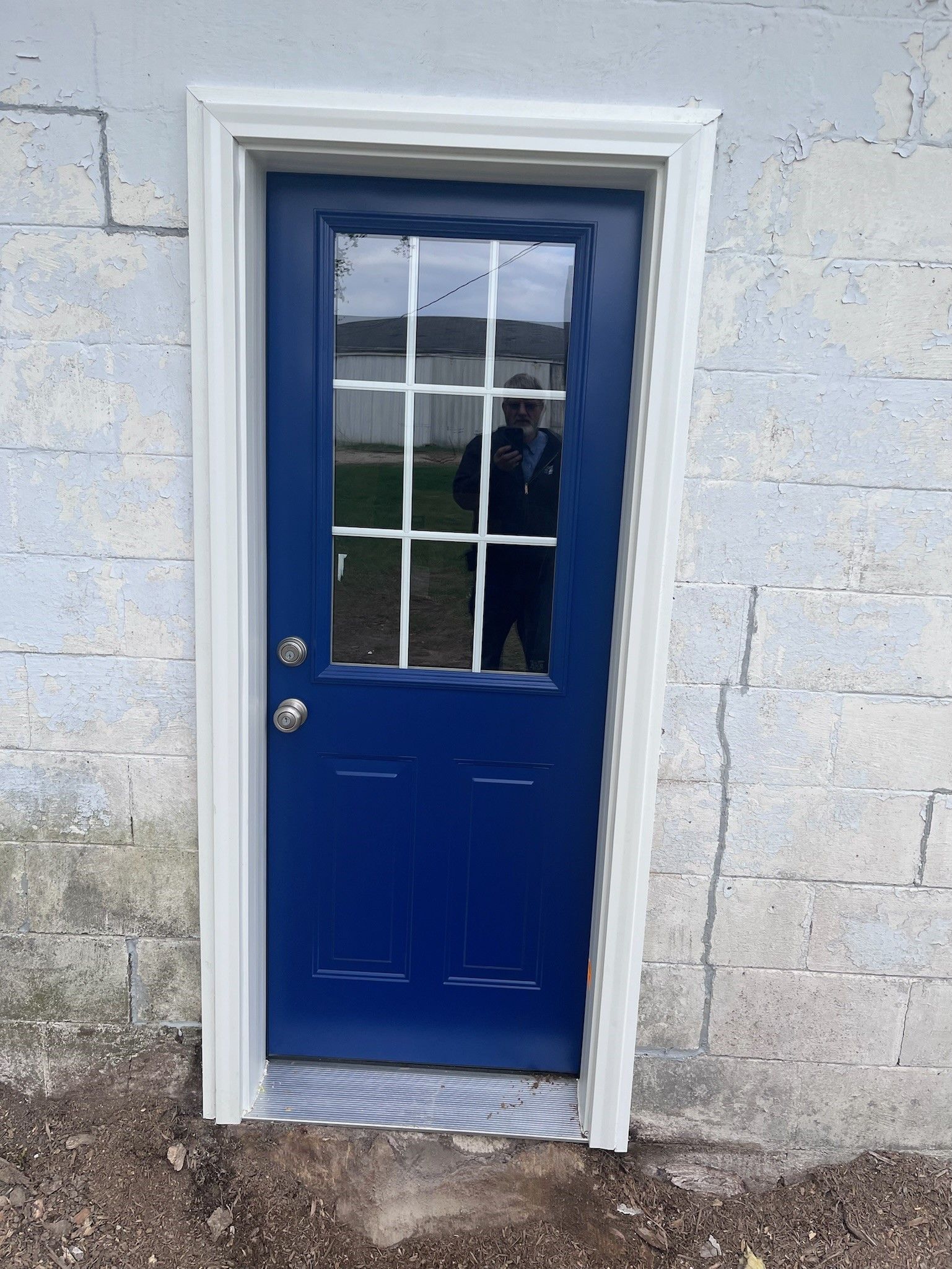 A blue door with a white trim is on a white brick wall.