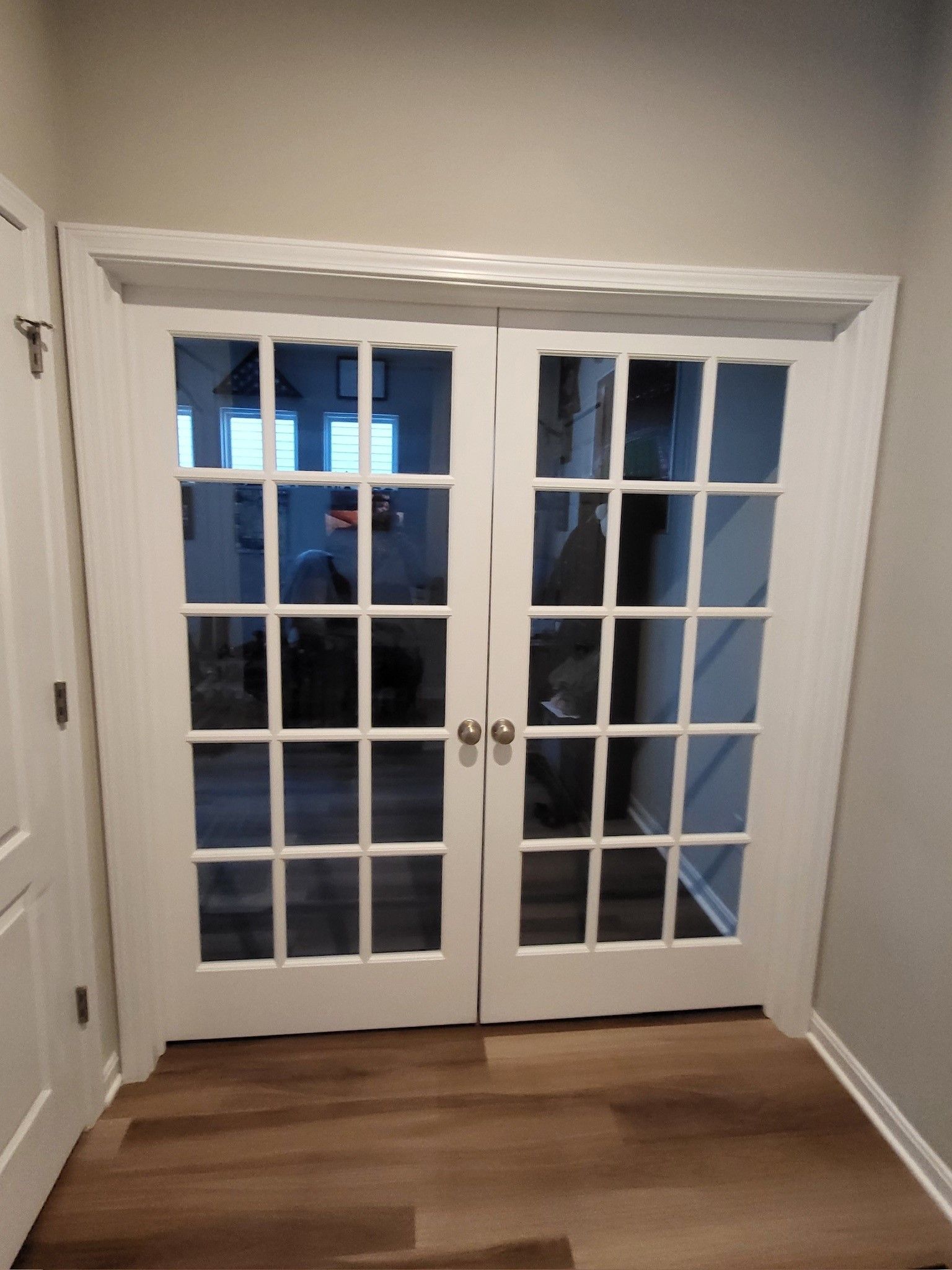 A pair of white french doors are open in a hallway.