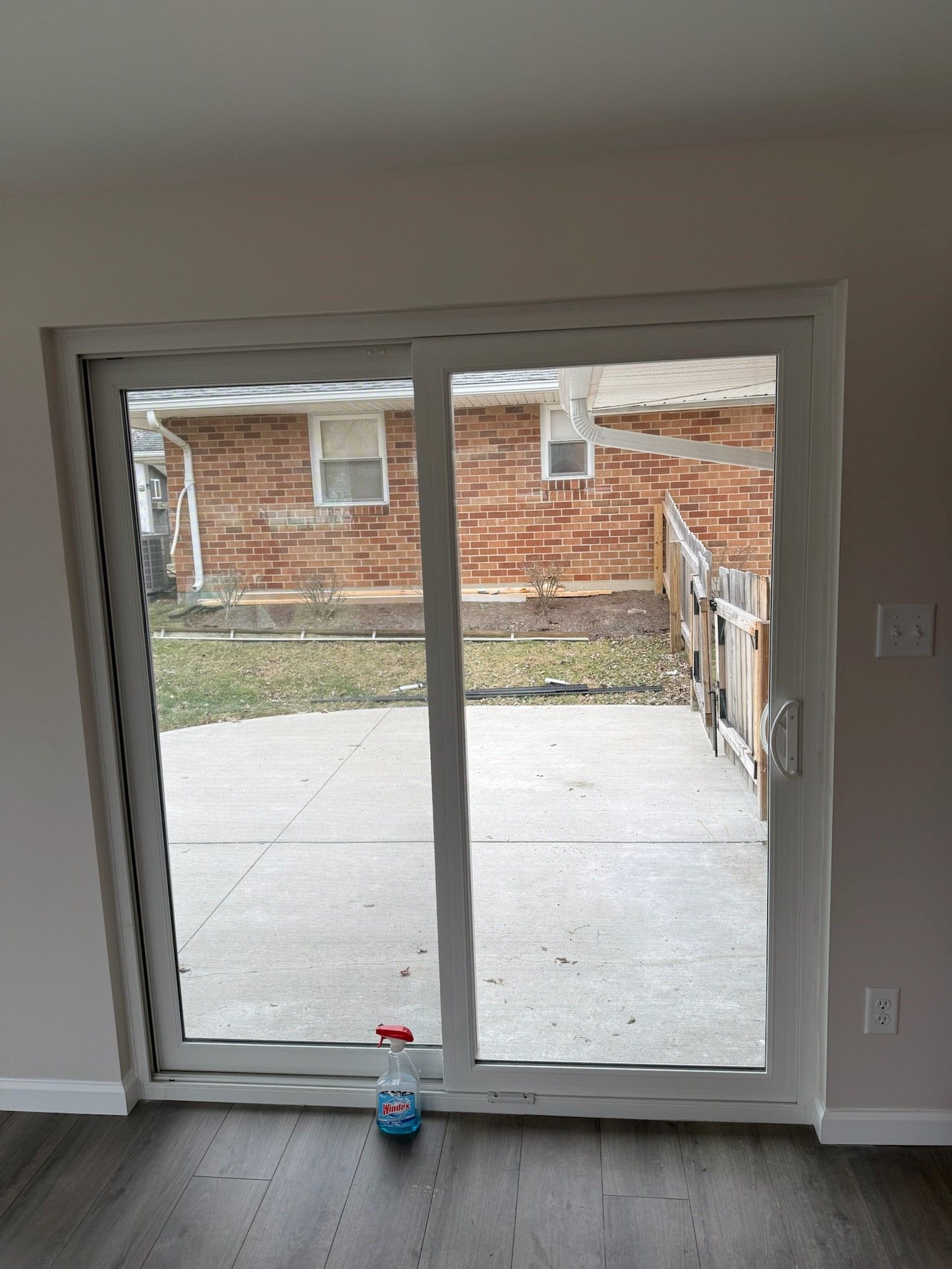 A room with a sliding glass door and a spray bottle on the floor.