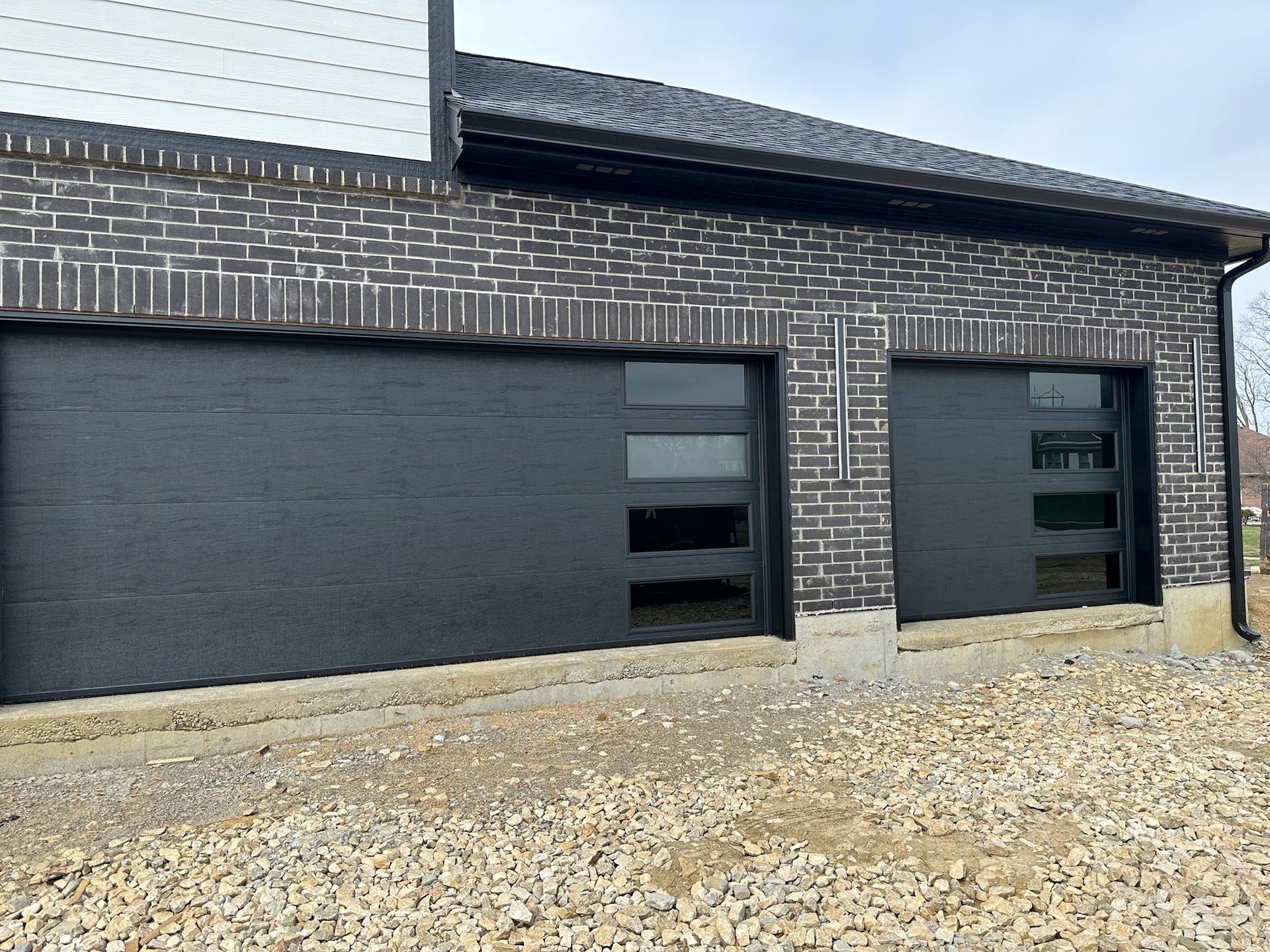 A black garage door is on the side of a brick building.