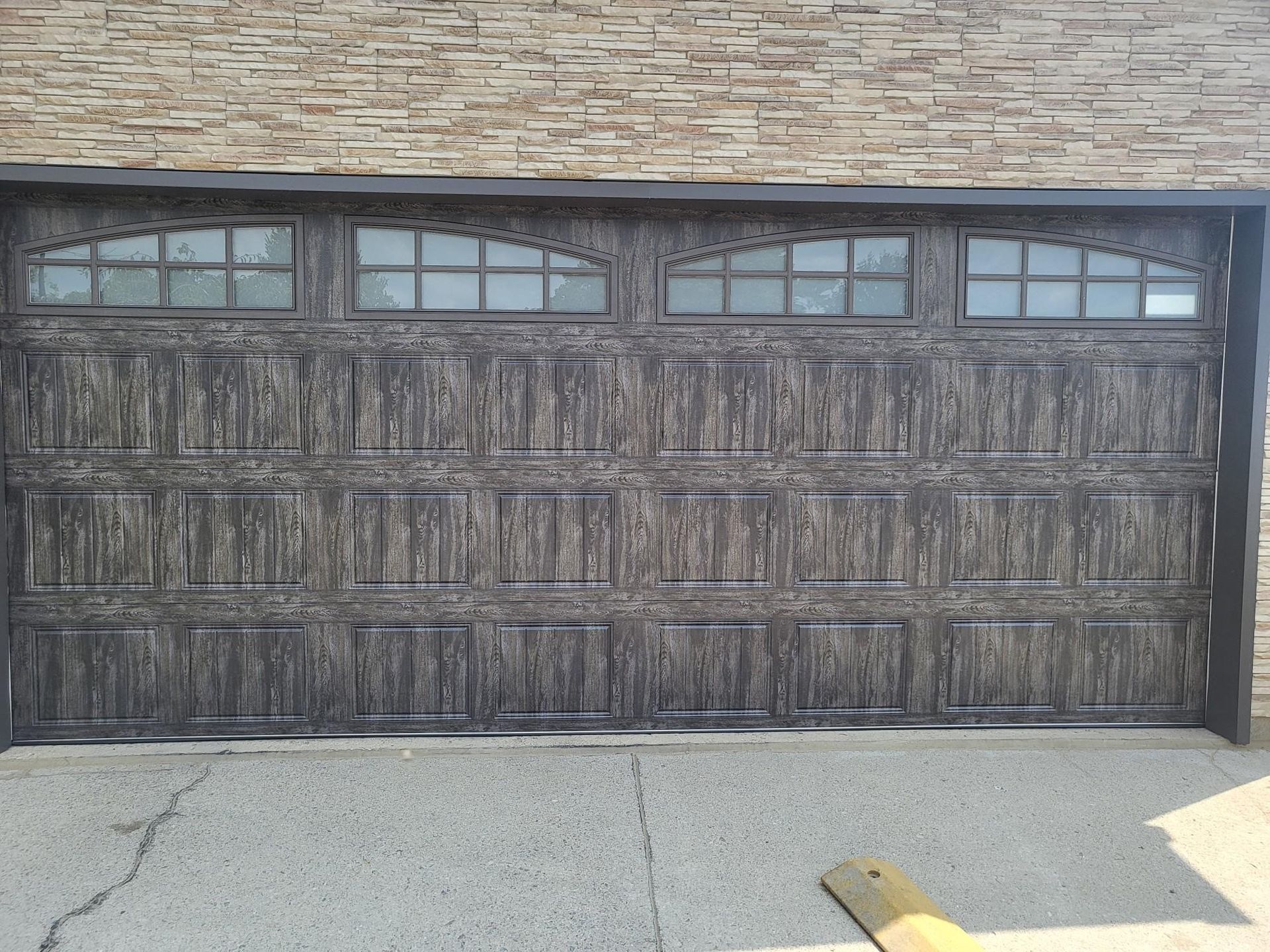 A large wooden garage door with a brick wall behind it.