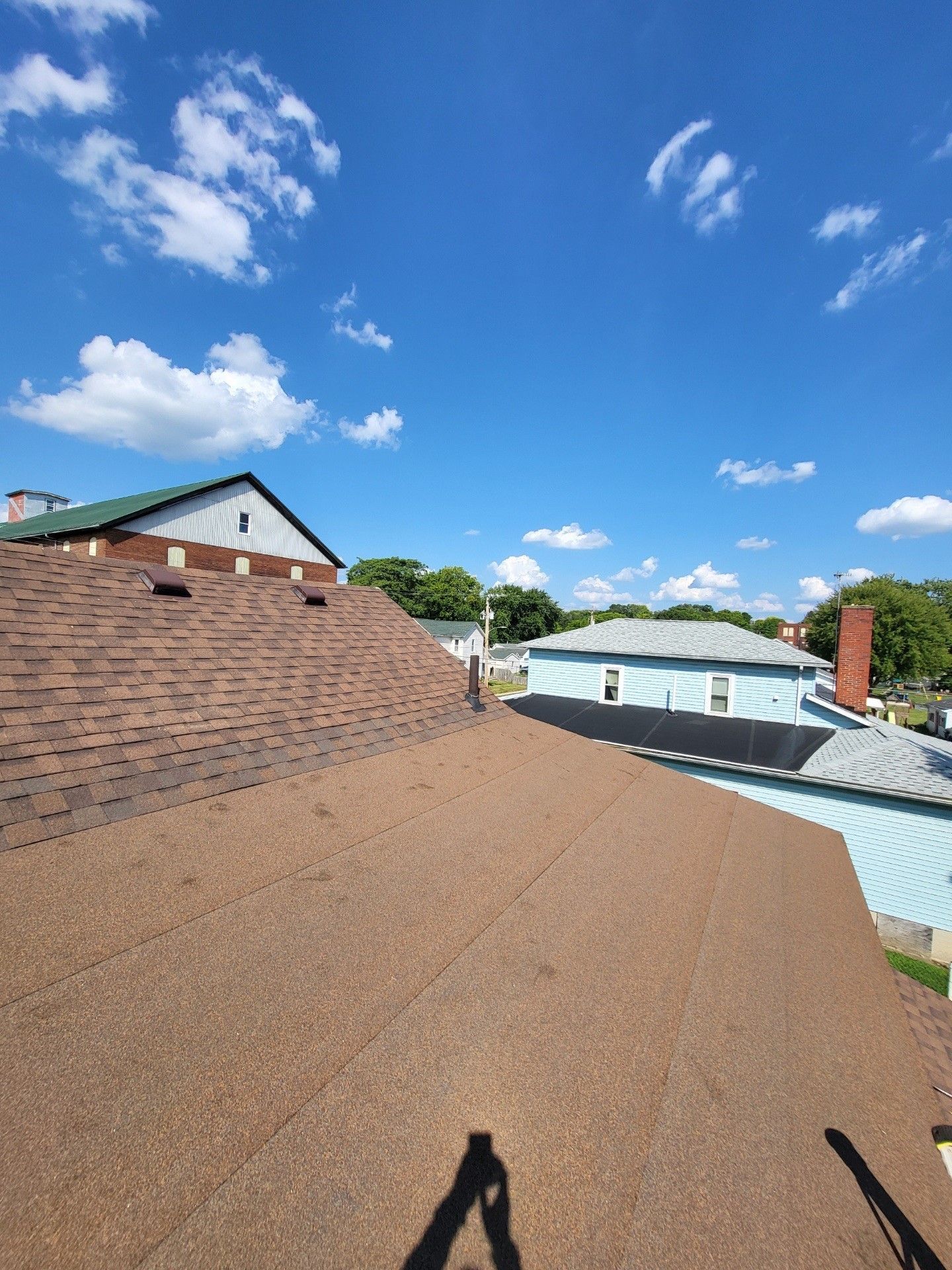 A flat rooftop view of a house with a blue sky and clouds in the background.
