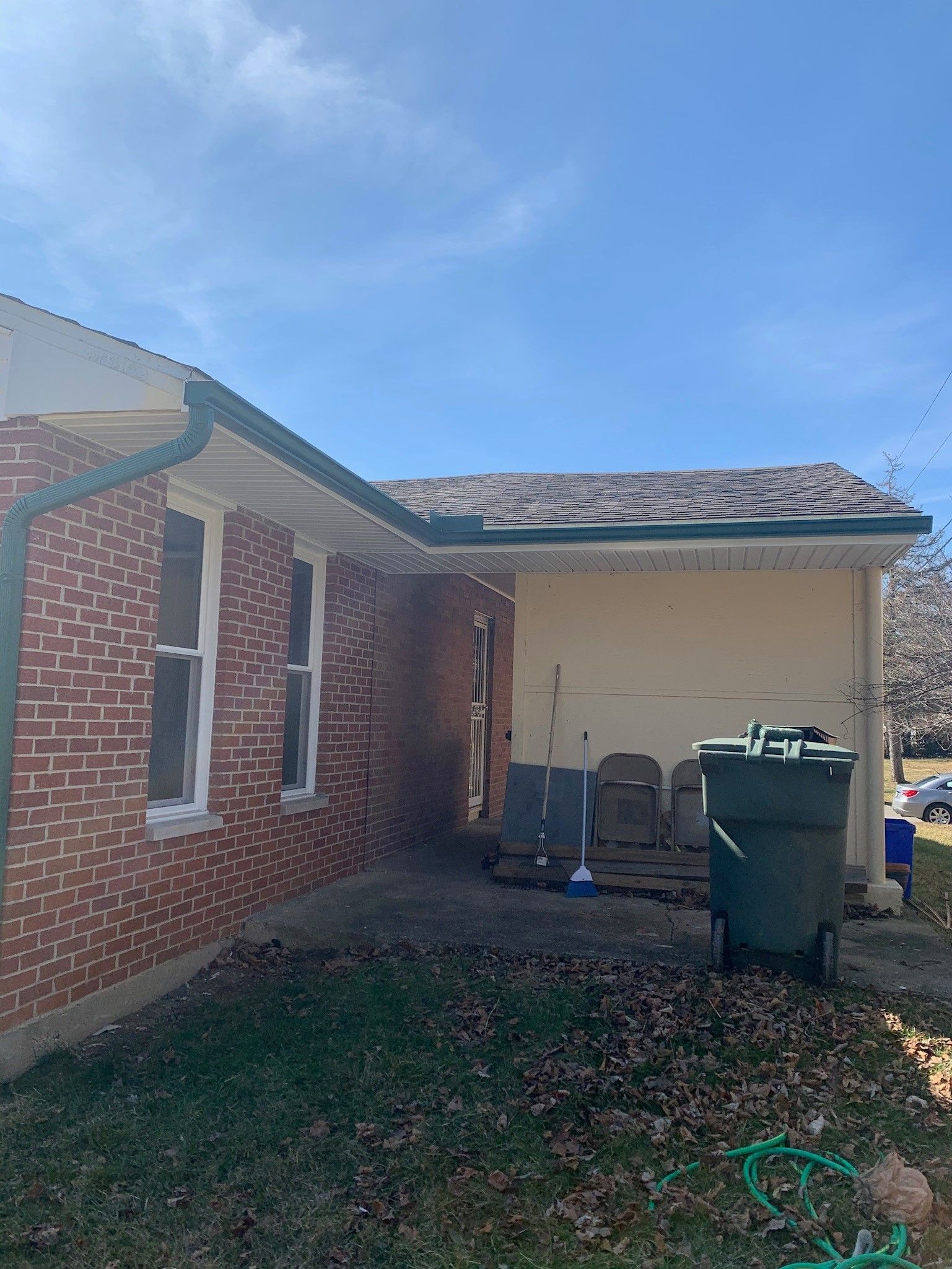 A brick house with a trash can in front of it.