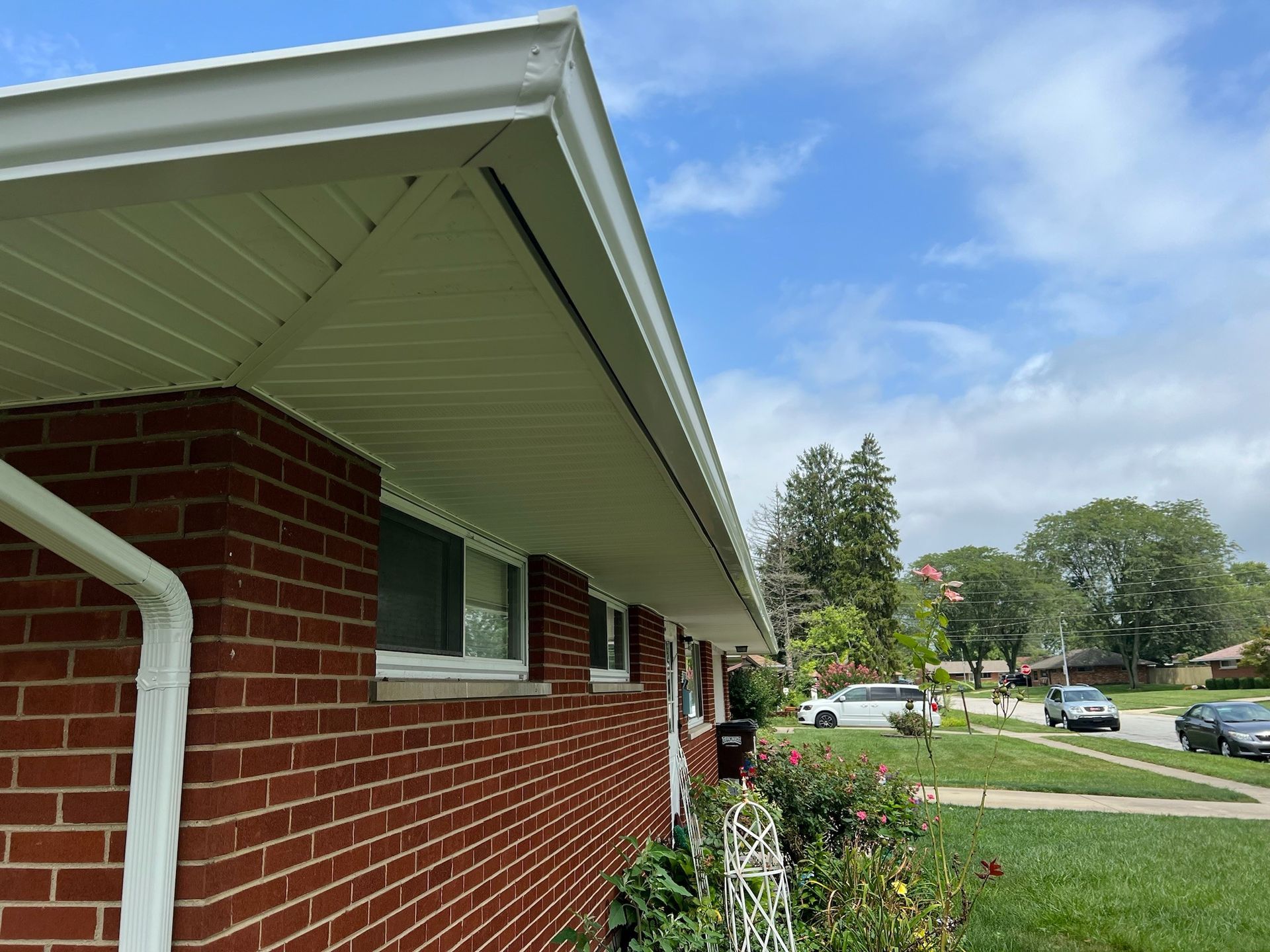 A red brick house with a white gutter on the side of it.