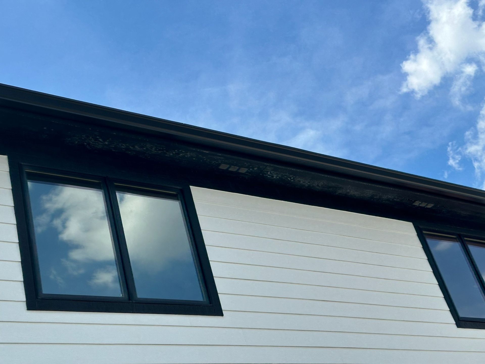 A black brick house with a large window and a camera on the roof
