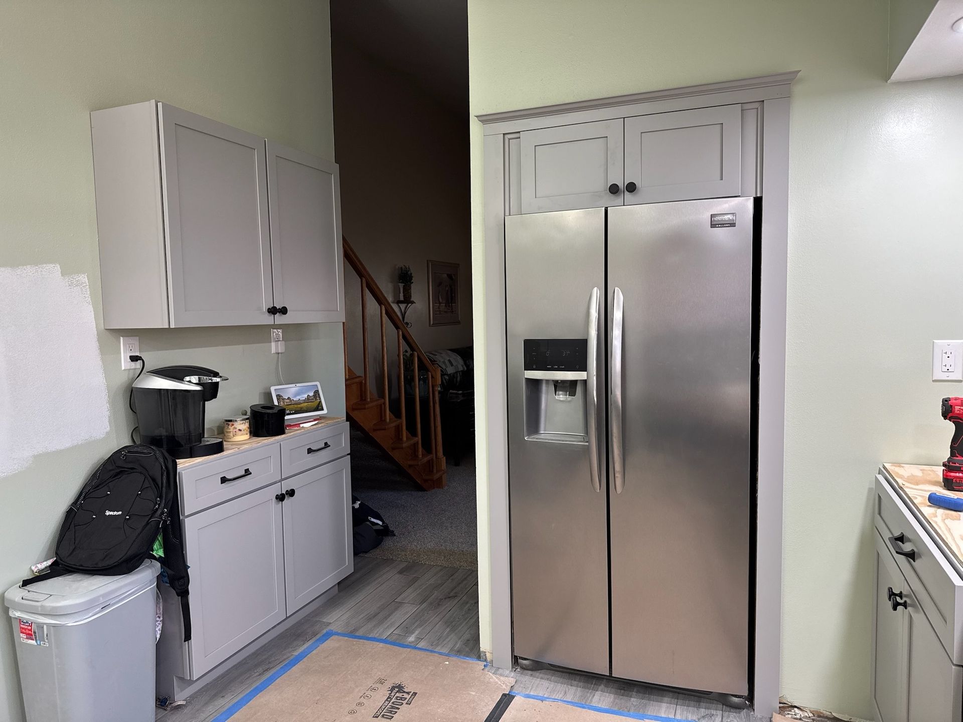 A kitchen with stainless steel appliances and gray cabinets is being remodeled.