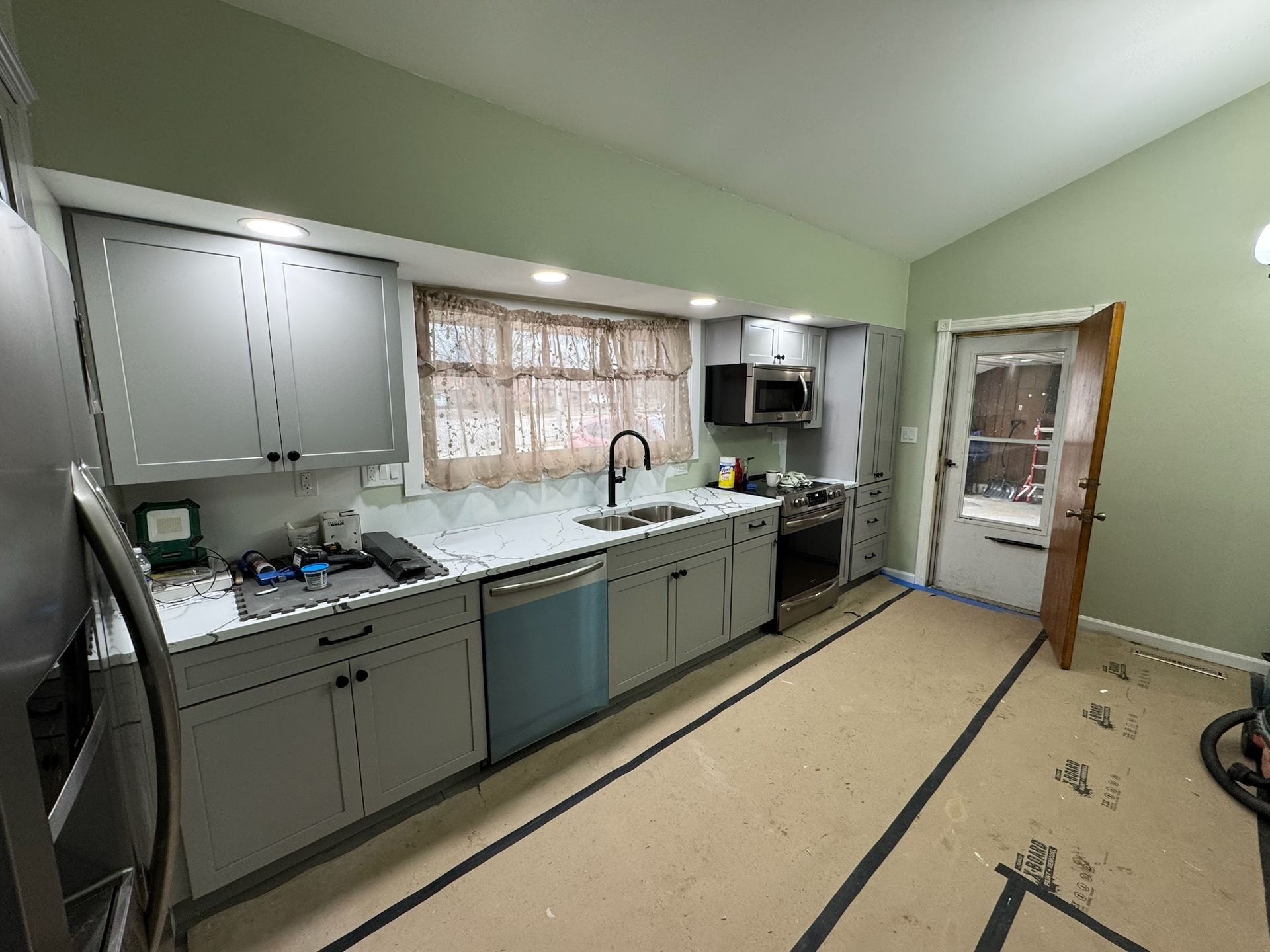 A kitchen with stainless steel appliances and gray cabinets is being remodeled.