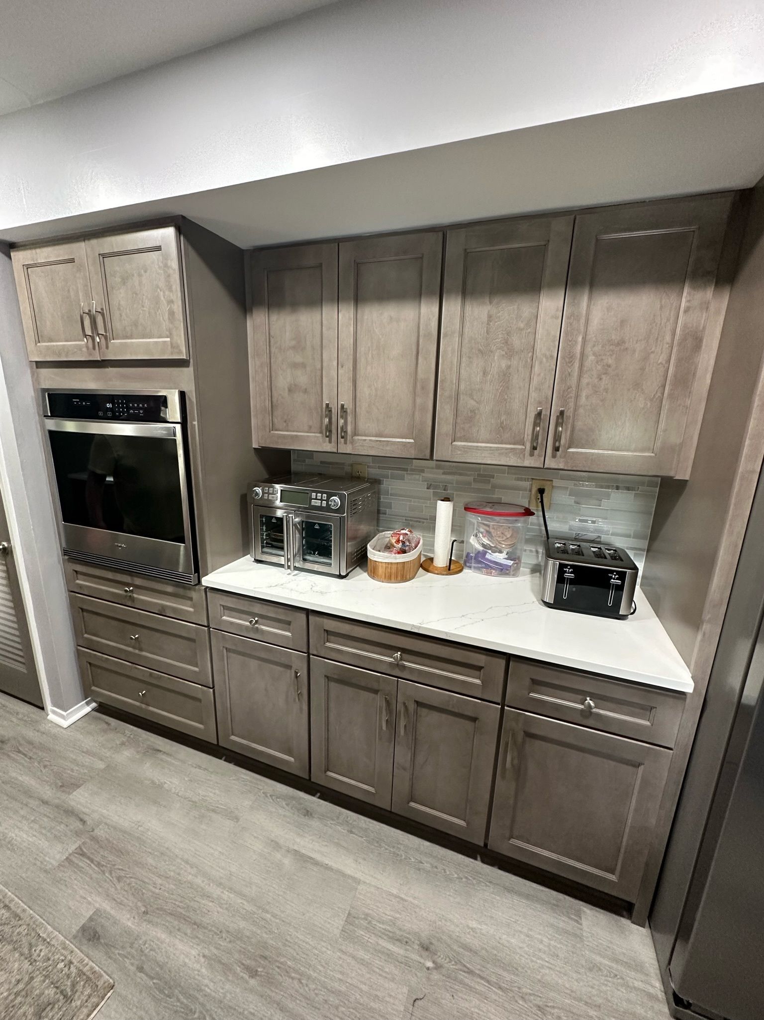 A kitchen with white cabinets , black counter tops , stainless steel appliances and a window.