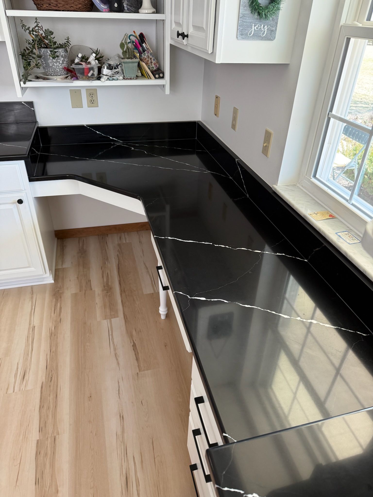 A kitchen with black granite counter tops and white cabinets.