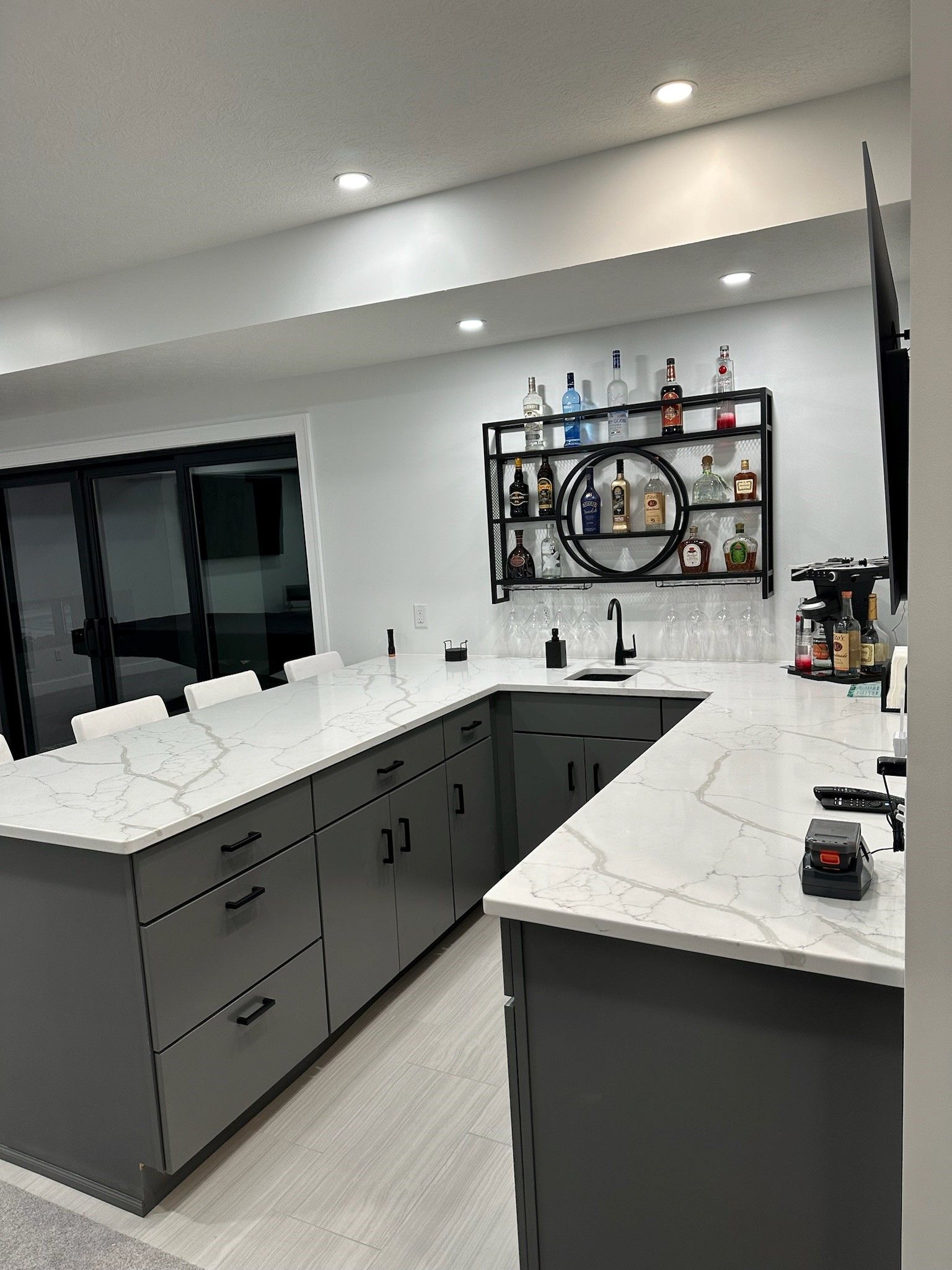 A kitchen with gray cabinets and white counter tops and a bar.
