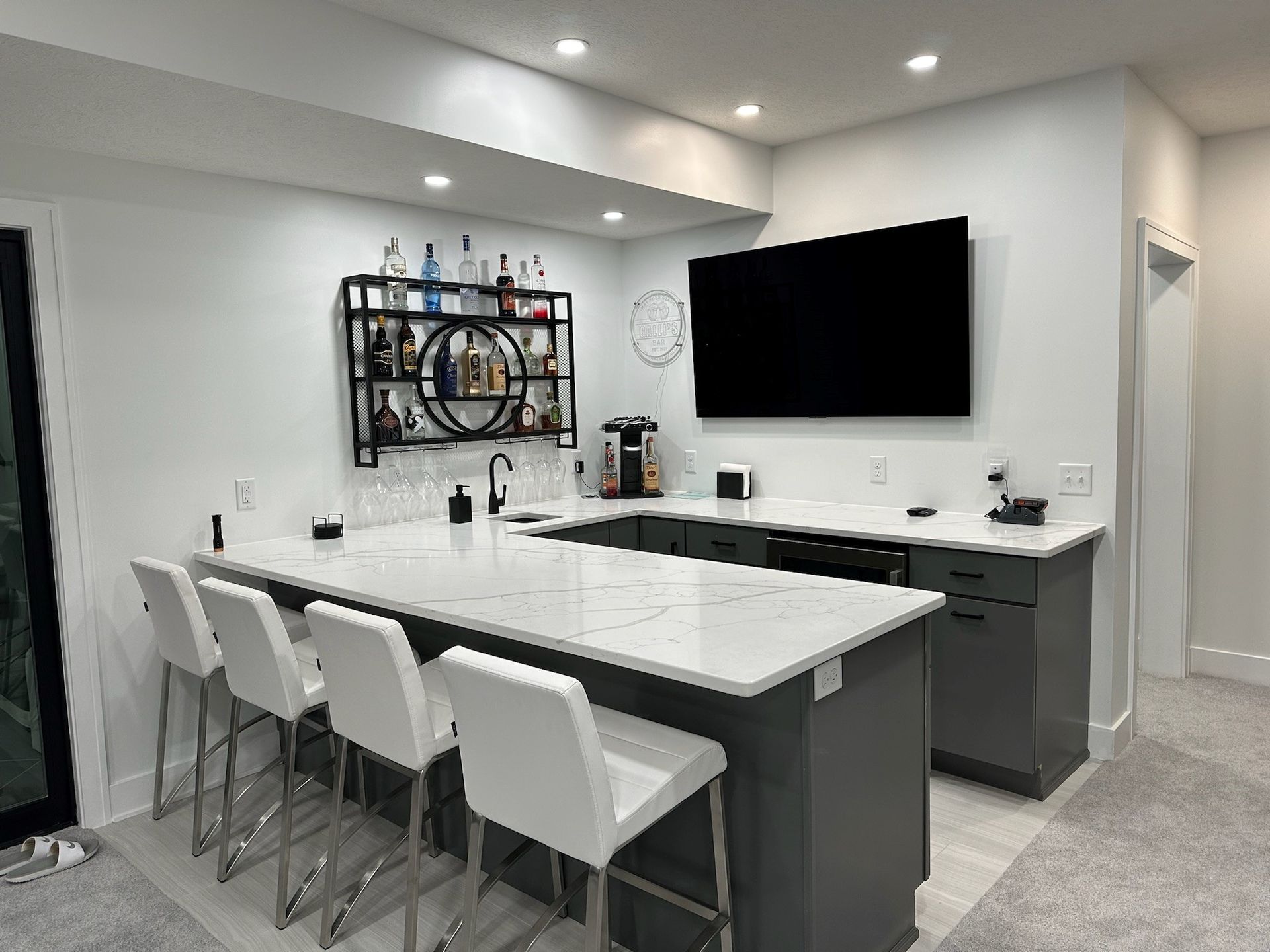 A kitchen with a bar and a flat screen tv on the wall.