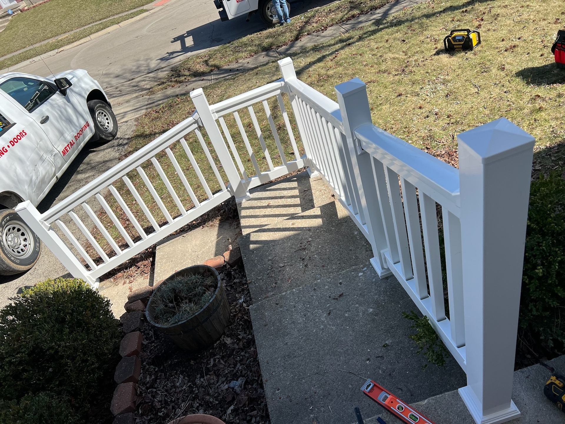 A white pick up truck is parked next to a white railing.
