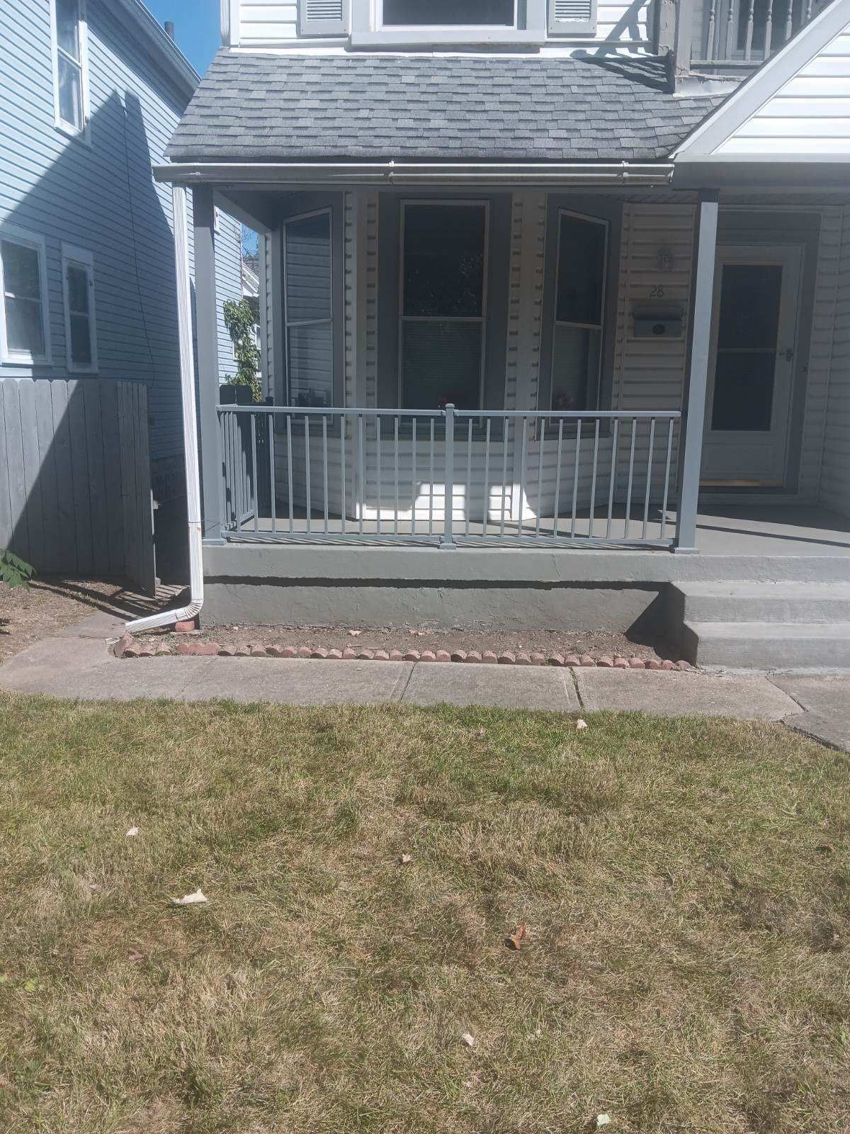 A house with a porch and a fence in front of it.