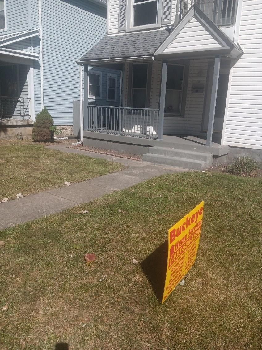 A yellow sign is sitting in front of a house.