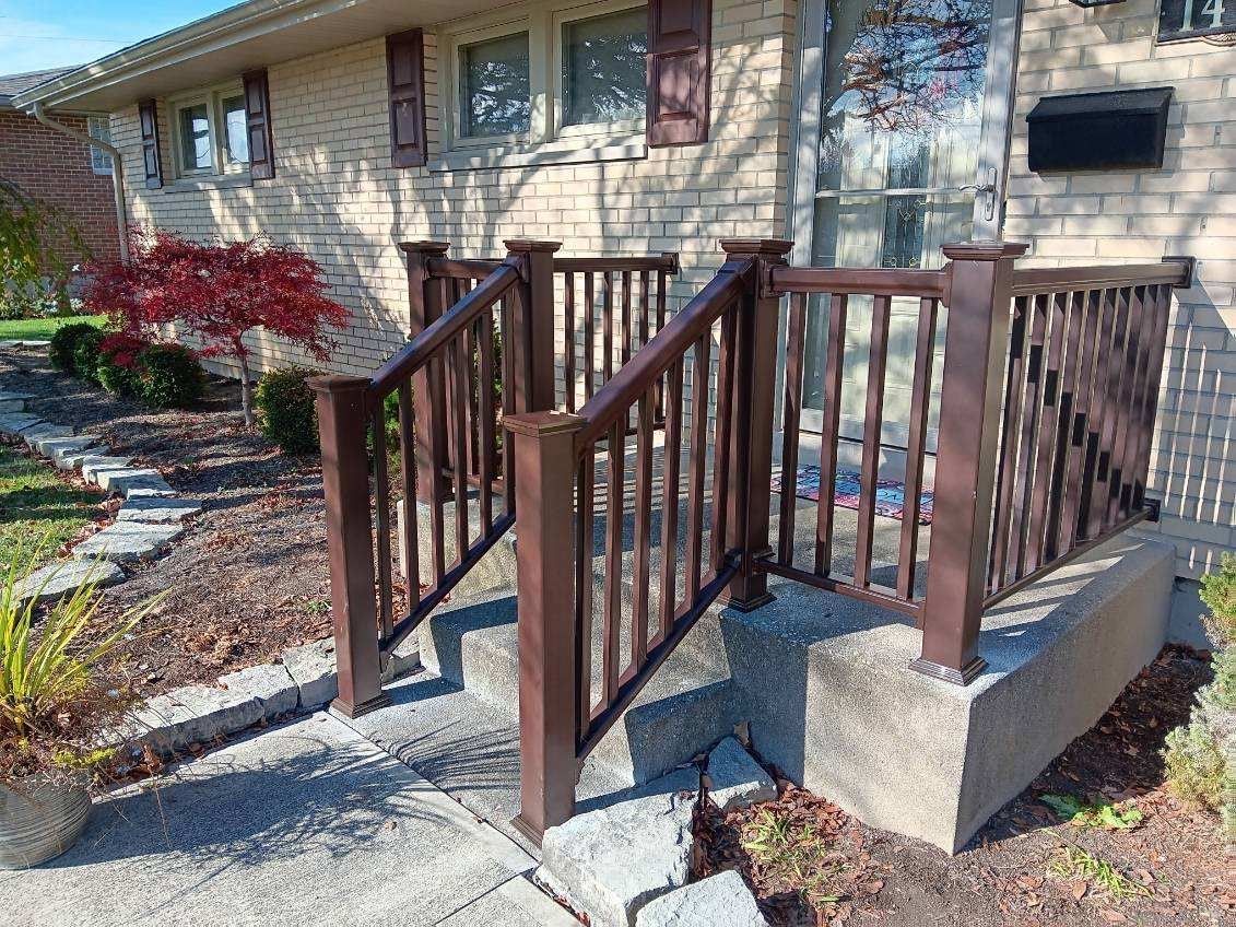 A brick house with a wooden railing and stairs leading to it.