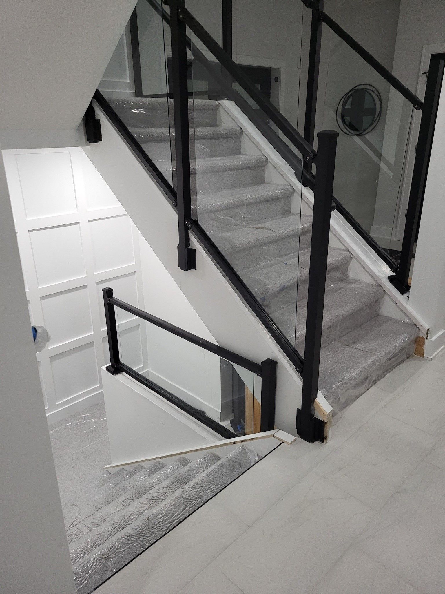 A staircase with a black railing and a glass railing.