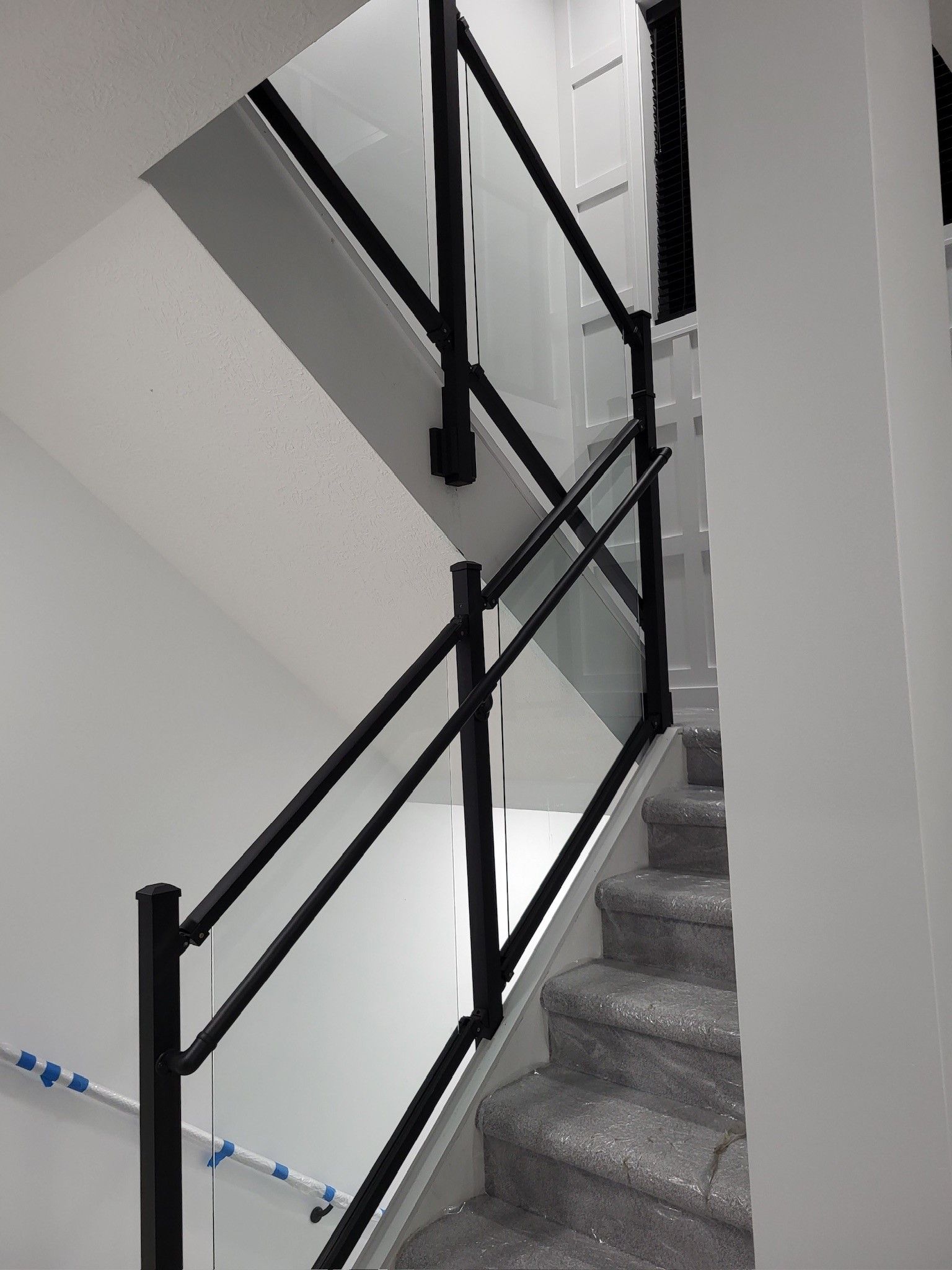 A staircase with a black railing and a white wall.