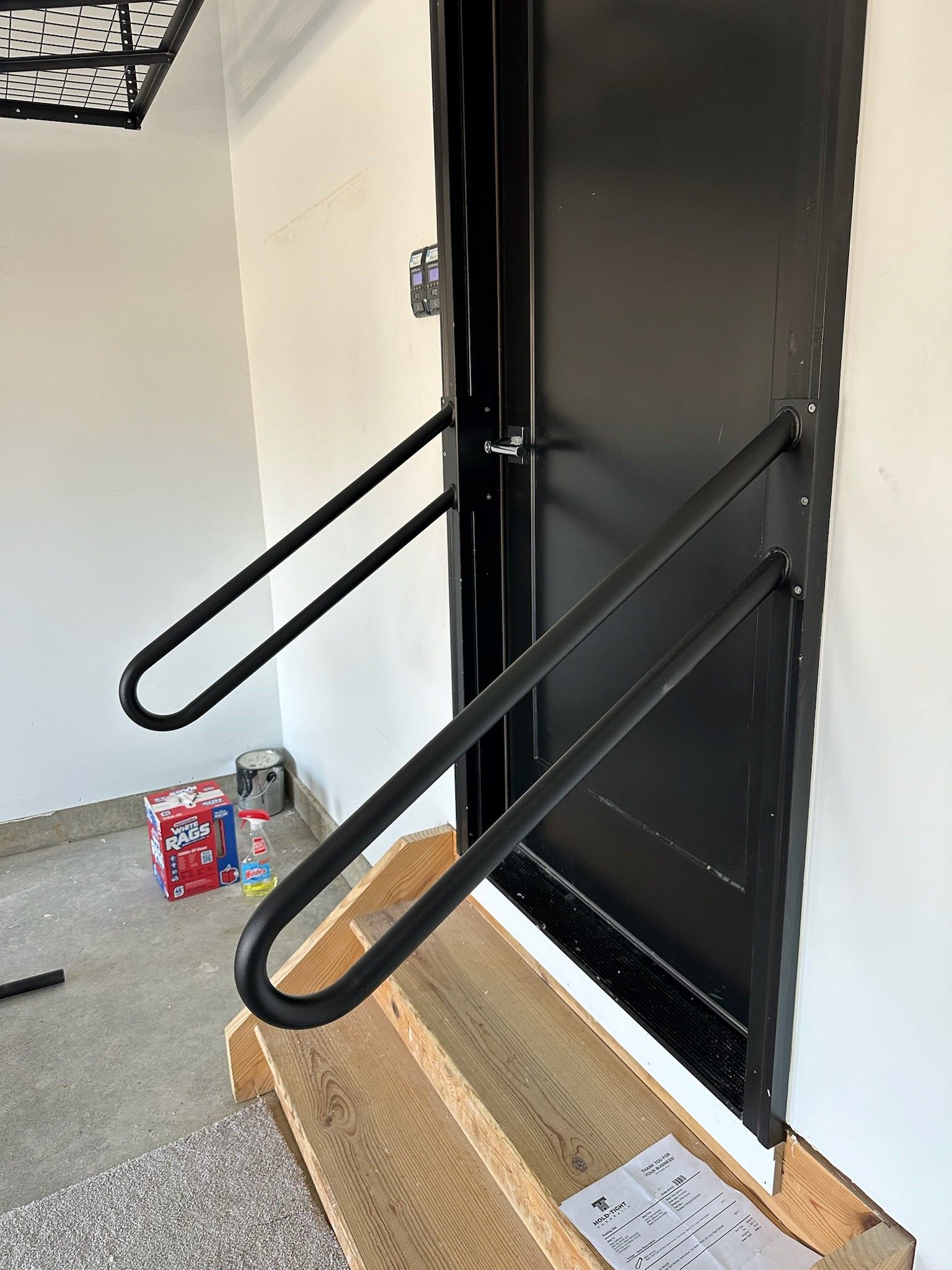 A black door with a metal railing attached to it.