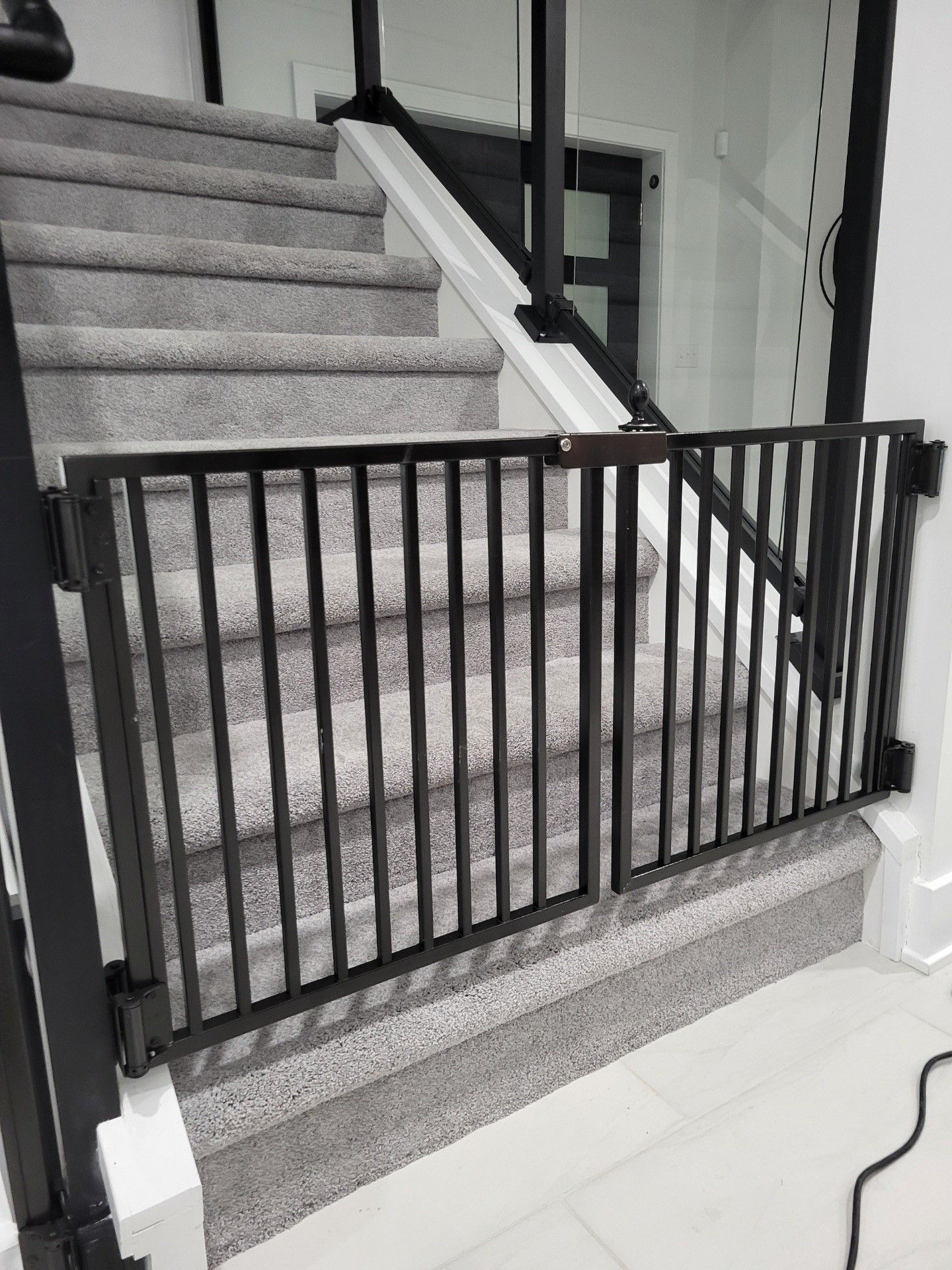 A baby gate is attached to the side of a set of stairs.