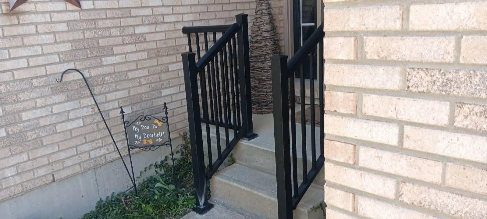 A brick wall with stairs leading up to it and a black railing.
