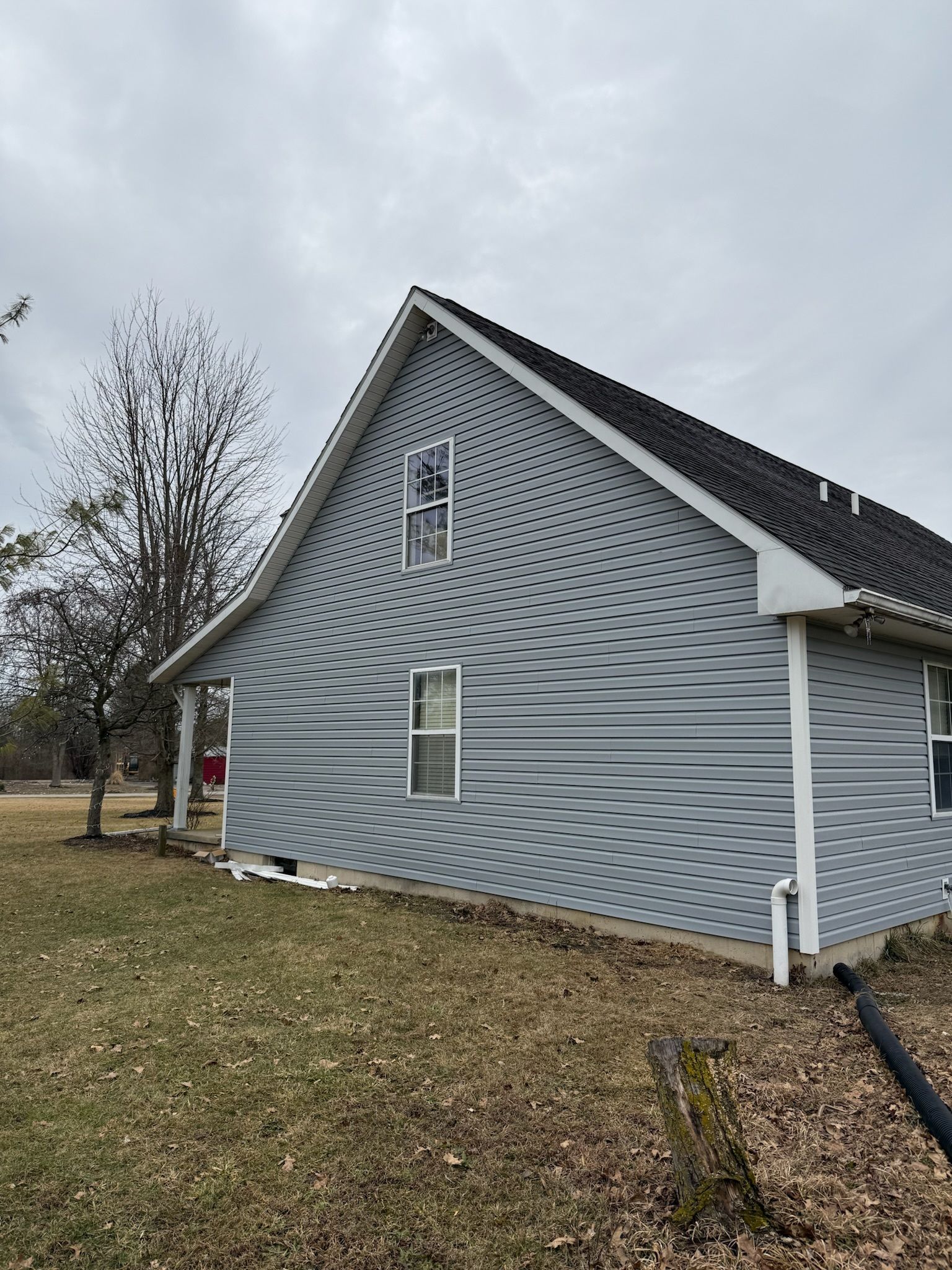 A house with a roof and a lot of windows is sitting on top of a lush green field.